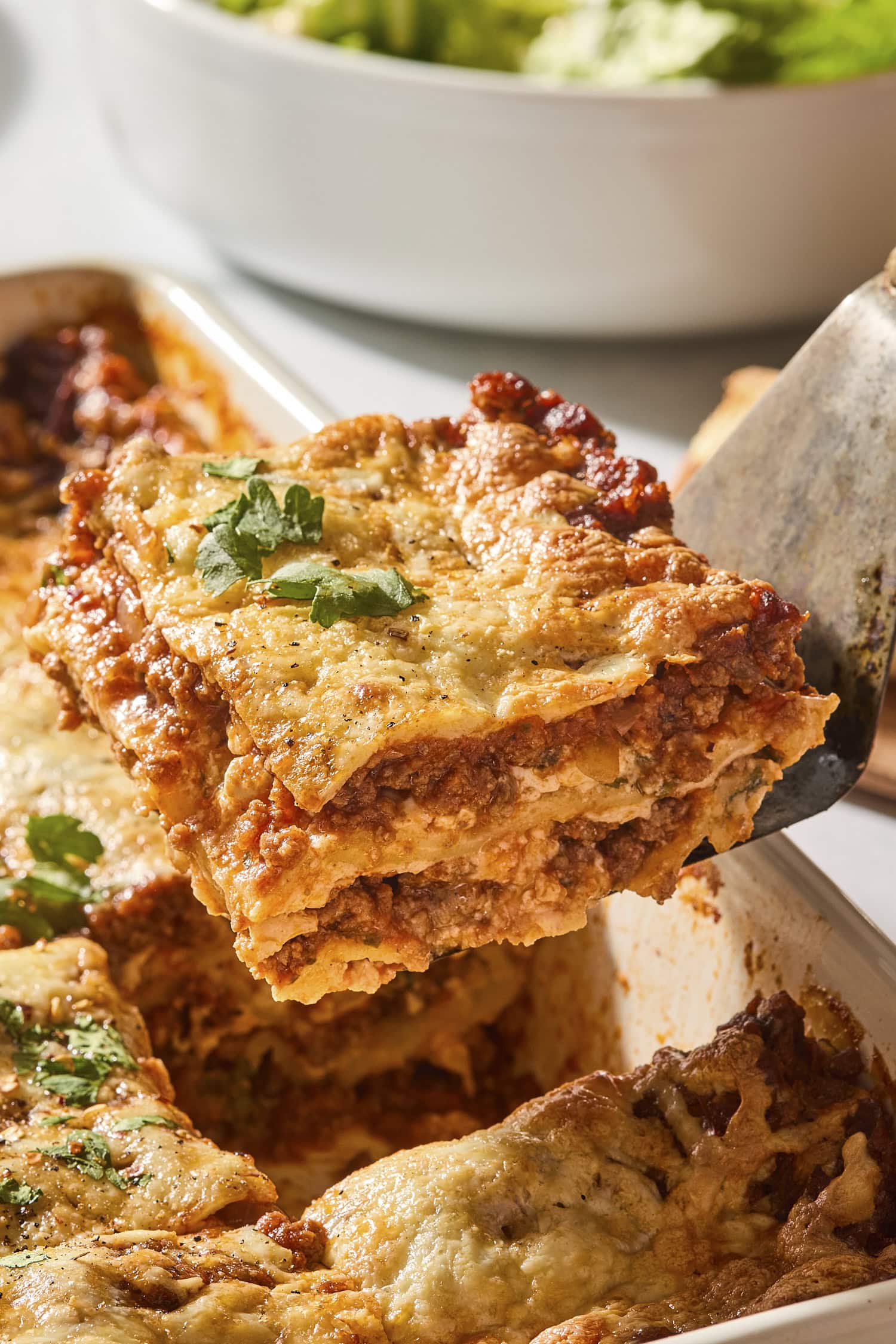 Slice of homemade lasagna being pulled from a pan.