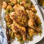 Whole roasted chicken with potatoes and broccoli on a platter.