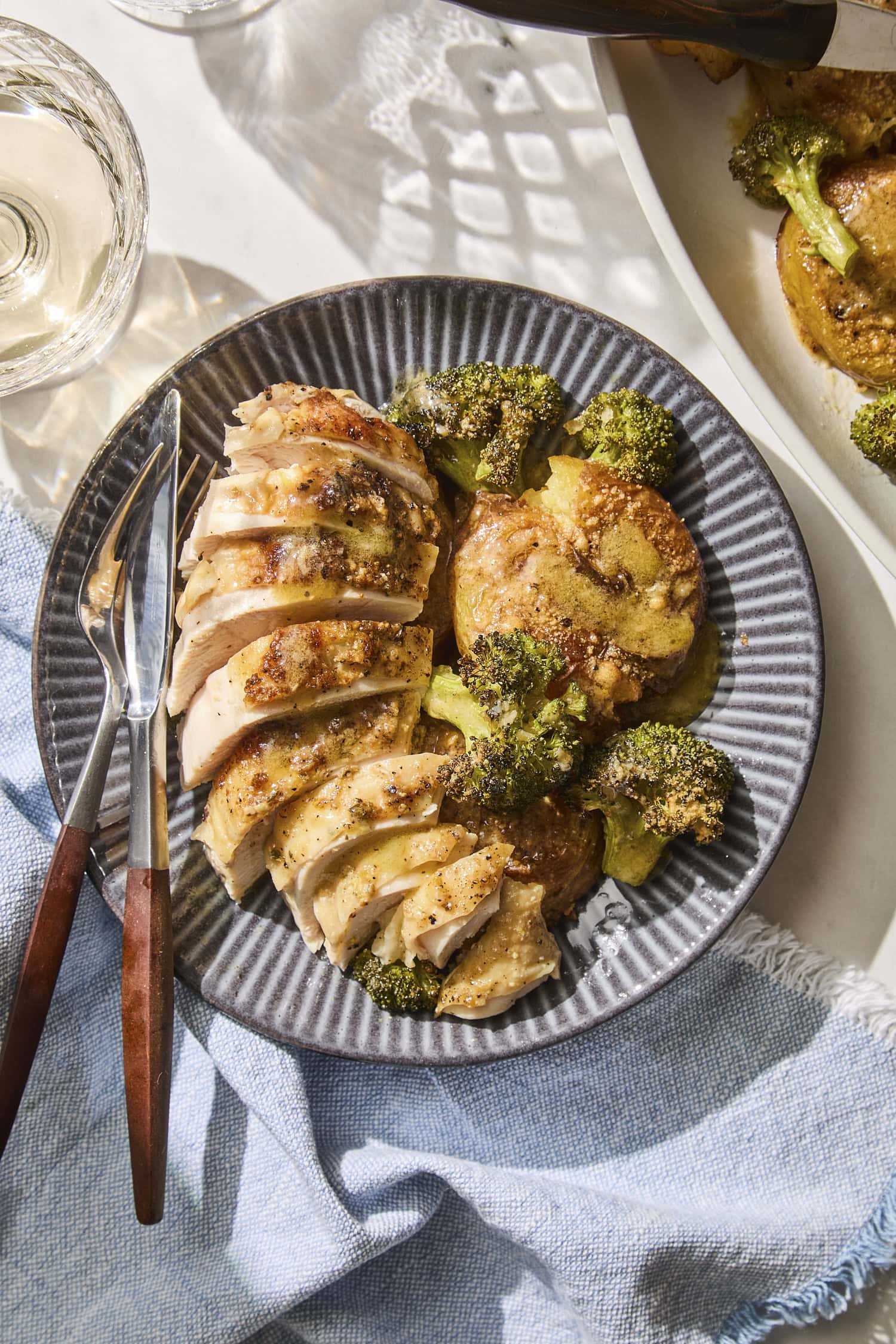 Sliced roasted chicken with potatoes and broccoli on a plate.