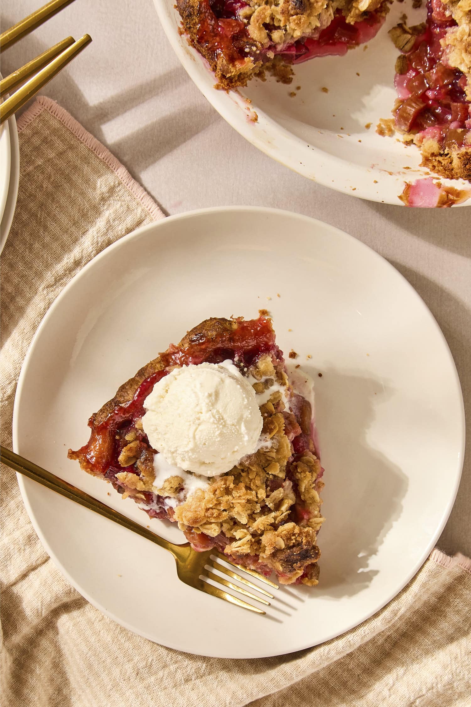 Slice of rhubarb pie on a plate with a scoop of ice cream.