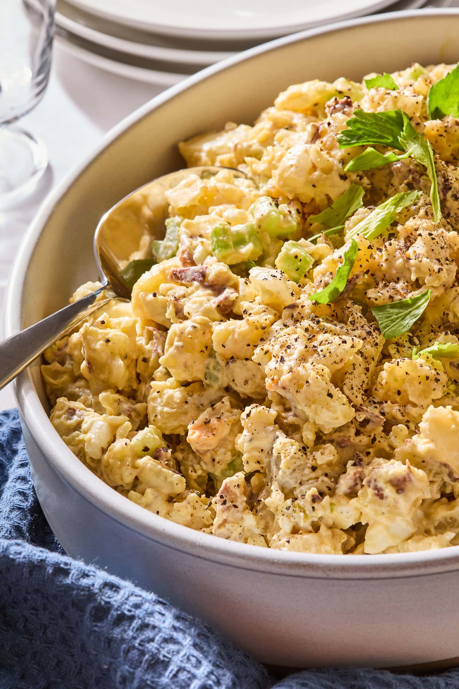 A serving spoon in potato salad in a serving dish.