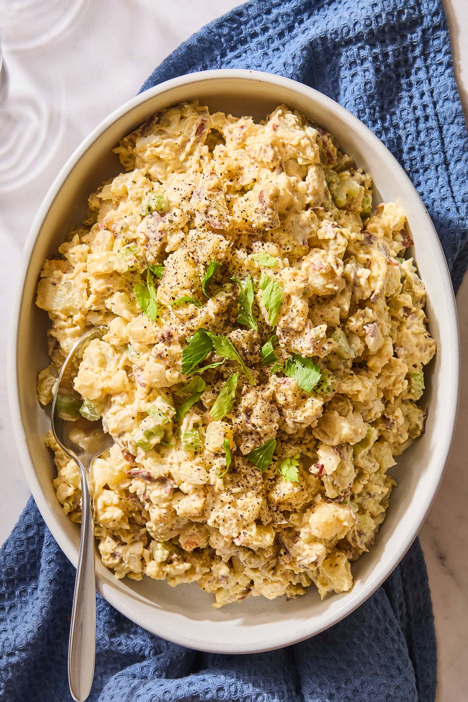 Potato salad in a large serving dish sitting on a towel.