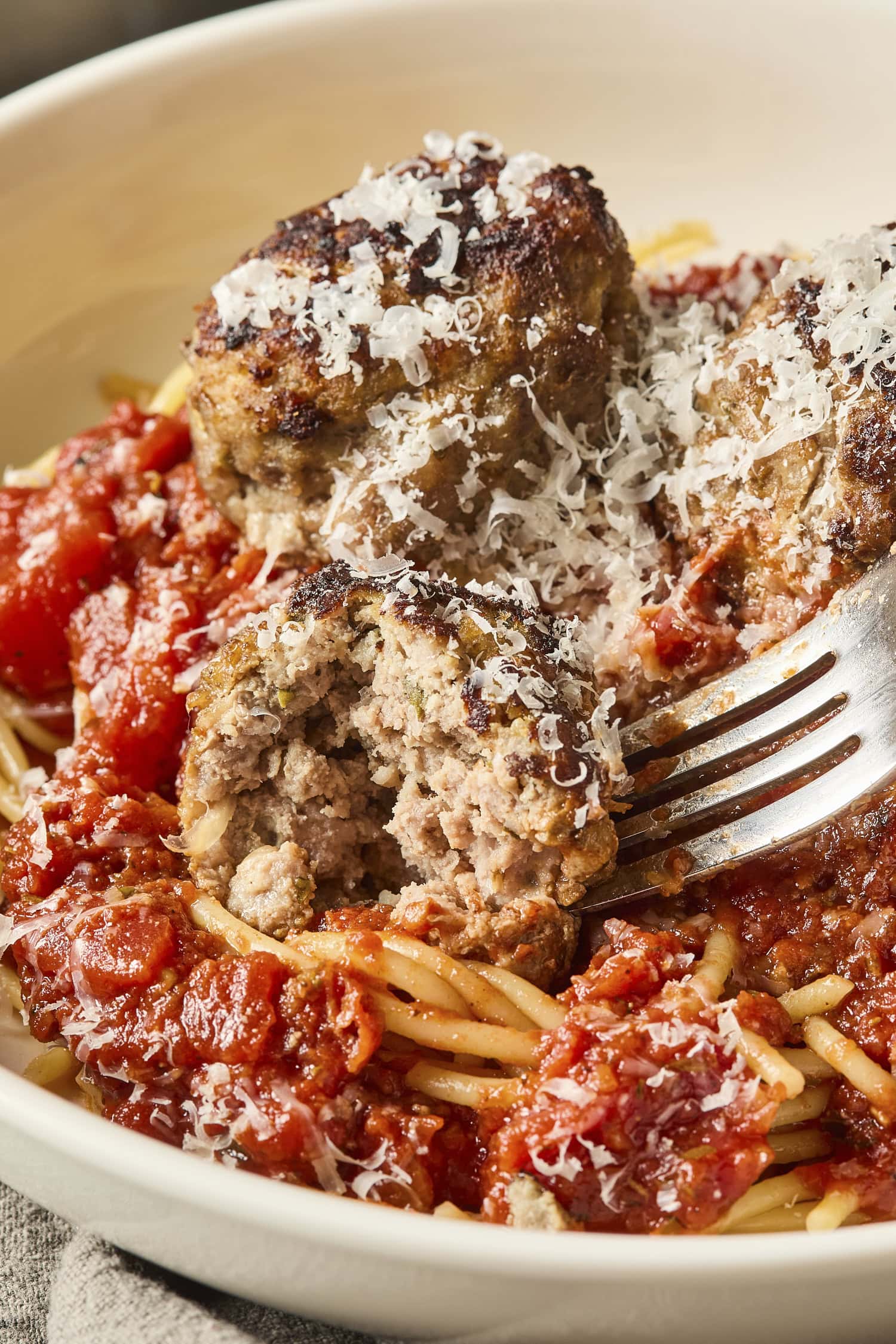 A meatball cut in half on a plate with spaghetti.