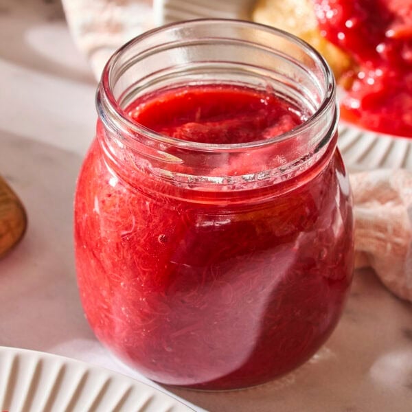Jar of strawberry rhubarb sauce with red color.