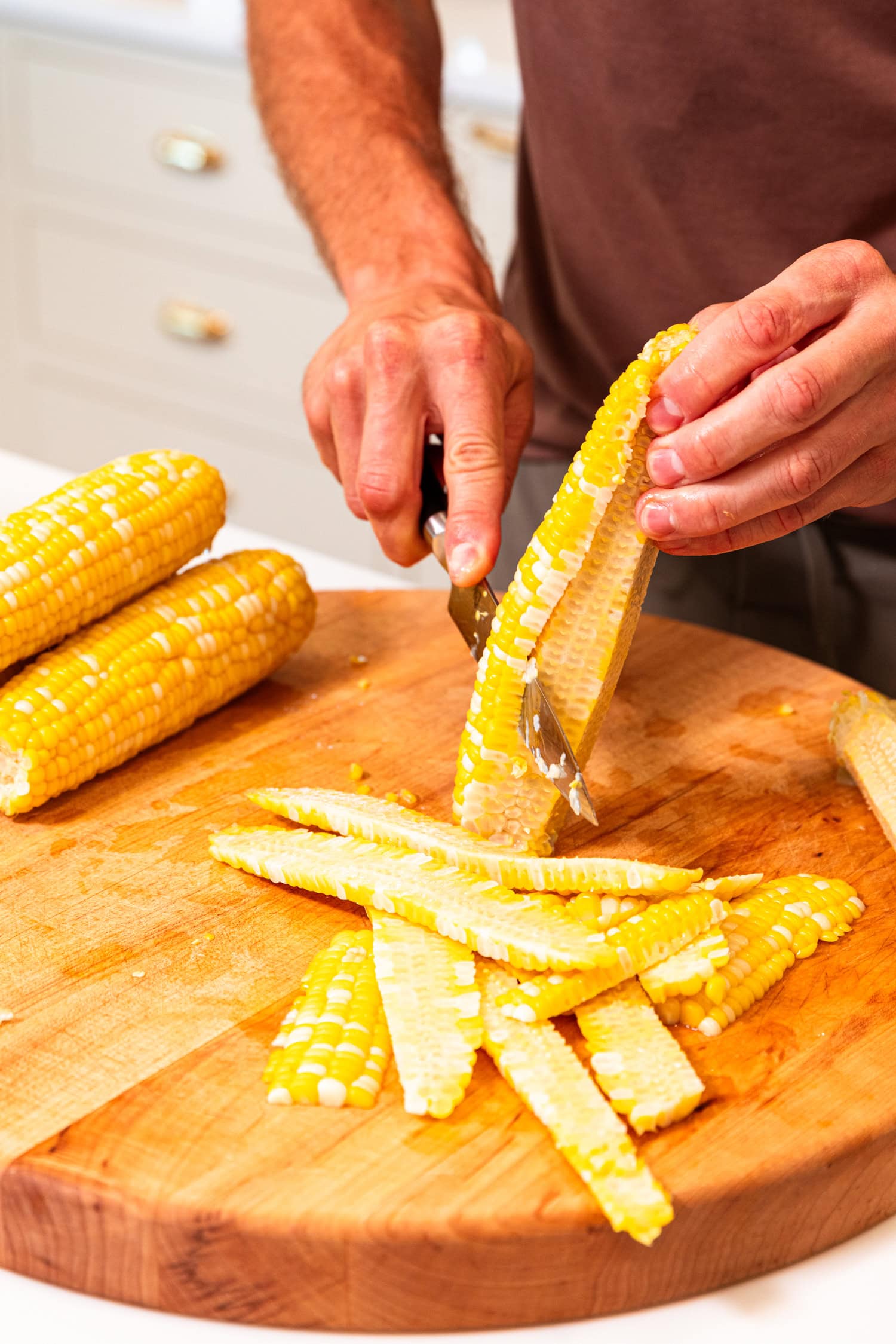 Slicing kernels off of ears of corn to freeze sweet corn.