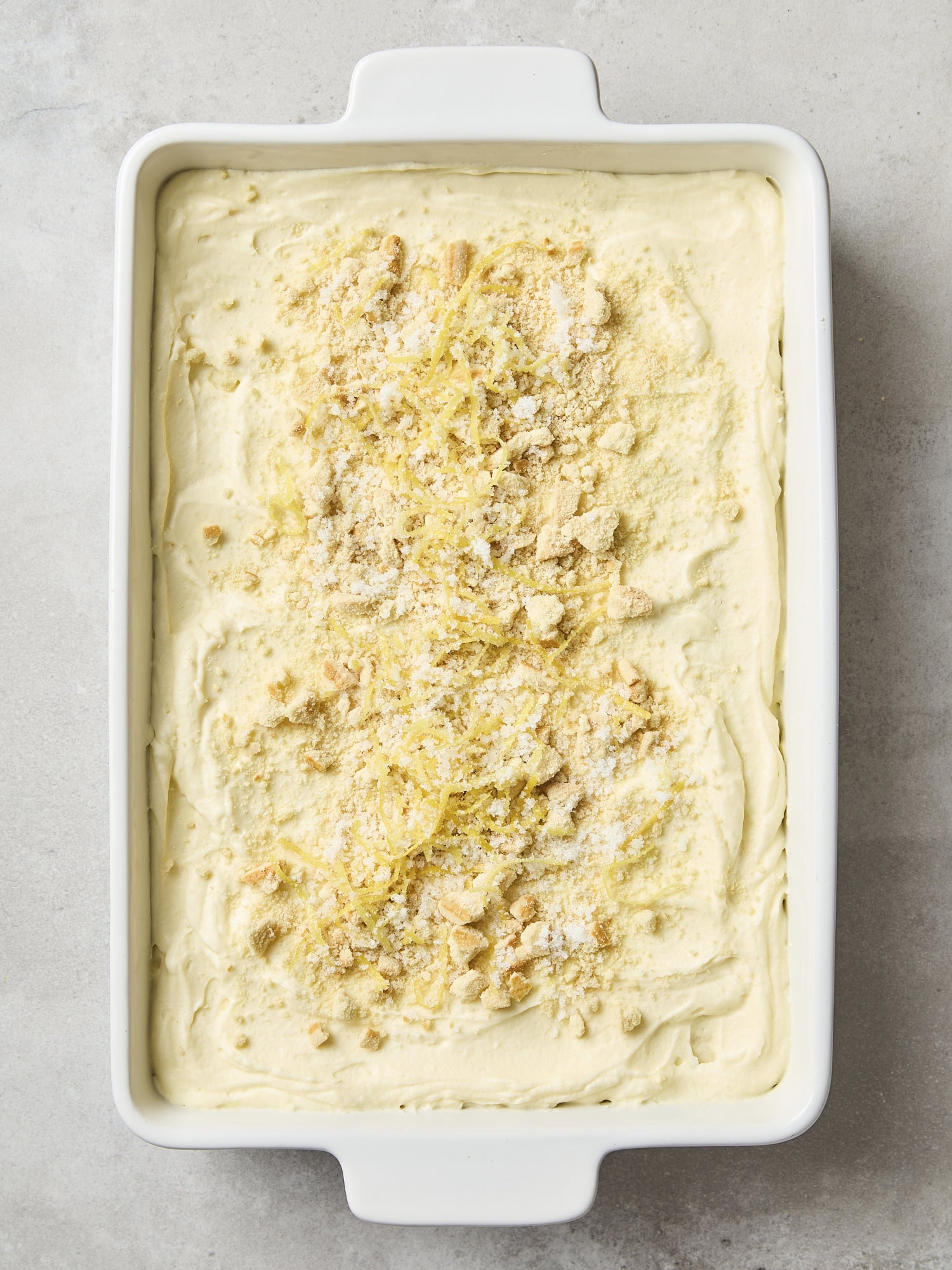 Lemon icebox cake assembled with crushed cookies and lemon zest on top.