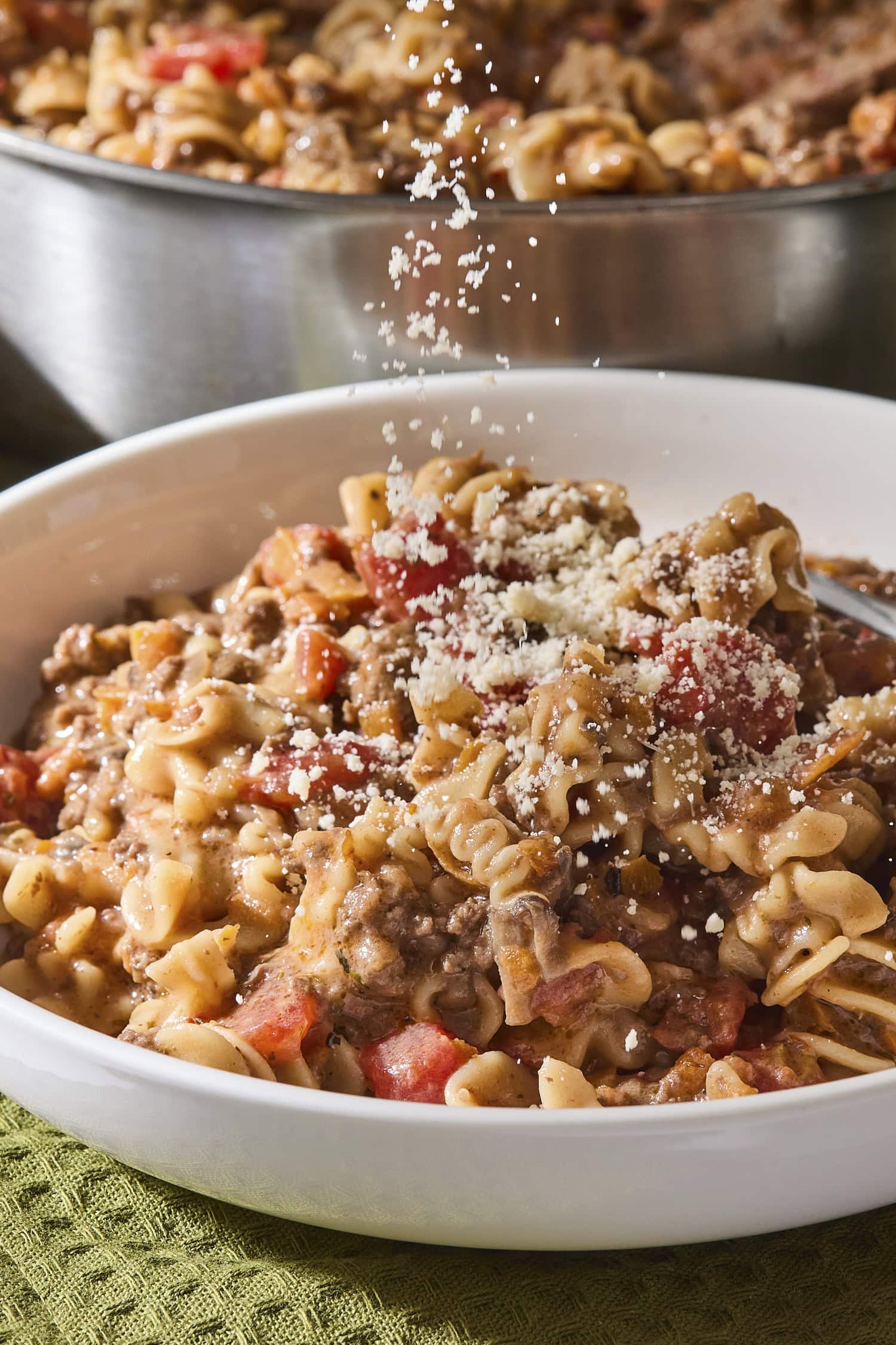 Parmesan sprinkling on top of bowl filled with beef ragu pasta.
