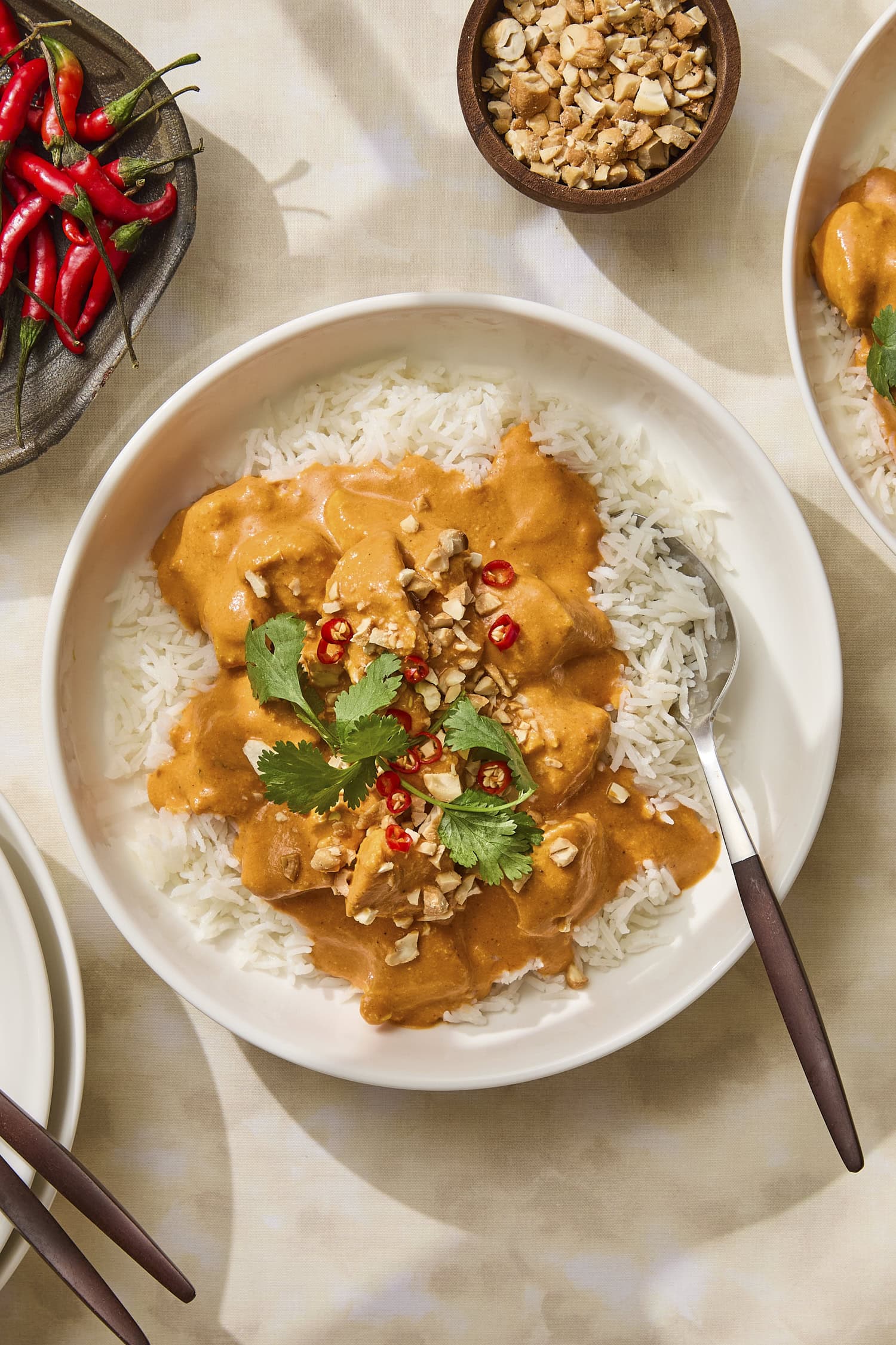 Bowl of butter chicken with chilis and cilantro on top.