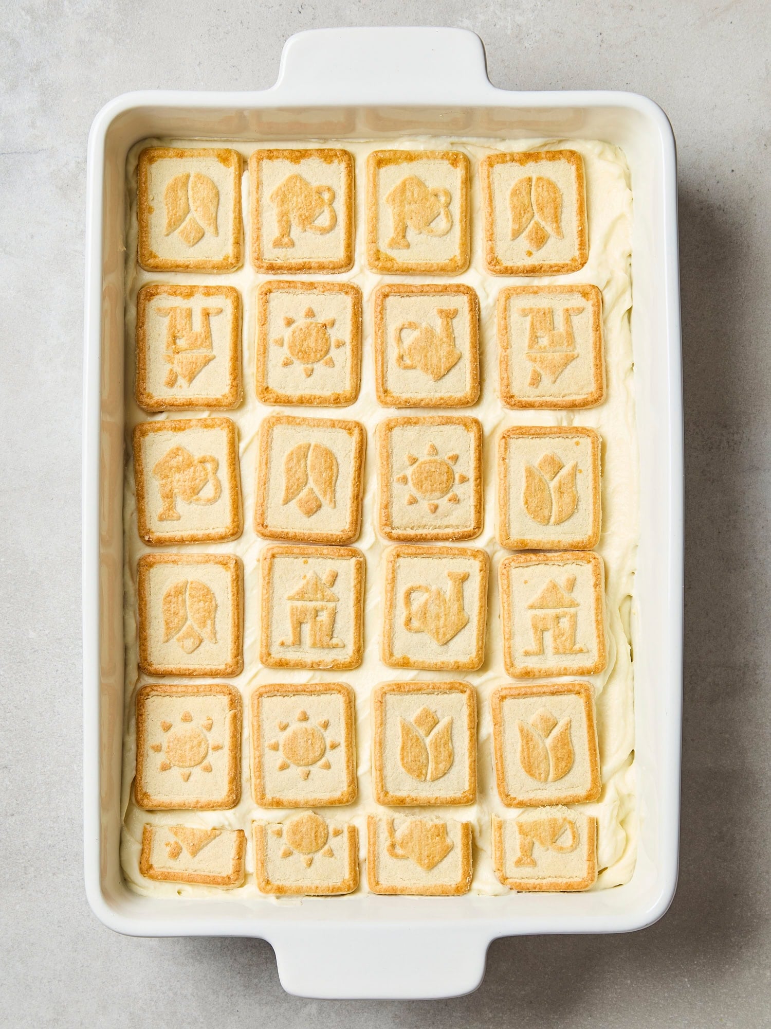 Butter cookies layered on top of lemon whipped cream mixture in baking dish.