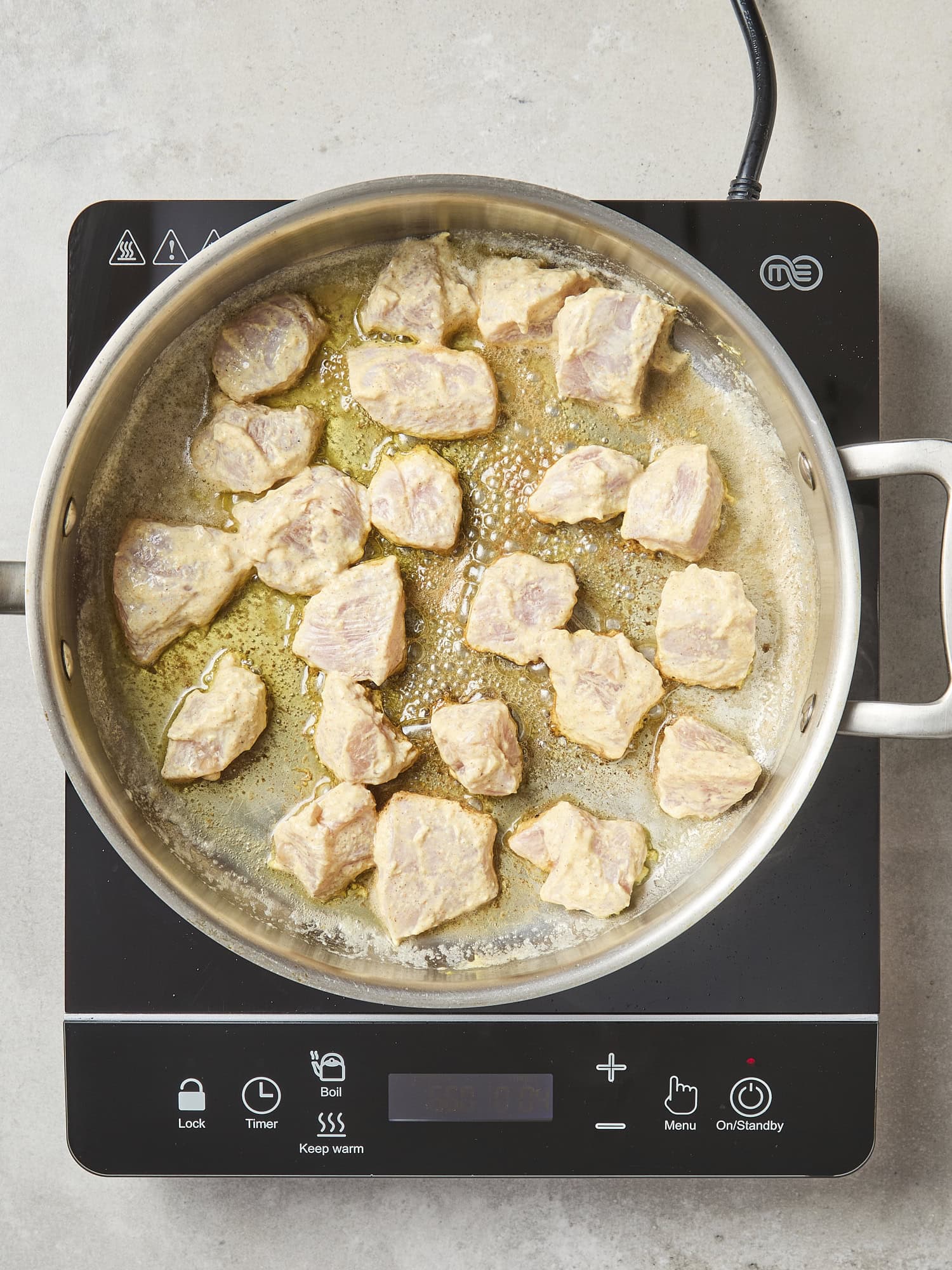 Pieces of raw chicken cooking in pan.