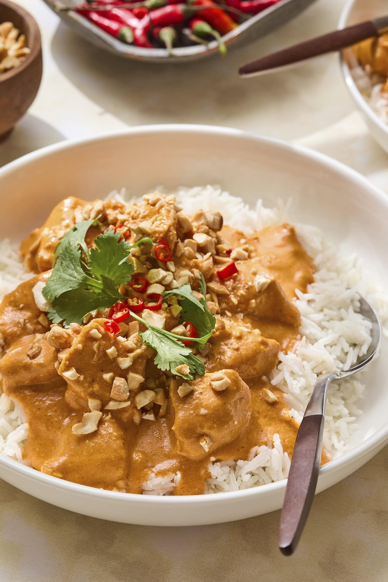 White rice with orange colored butter chicken with cashews and cilantro on top.