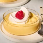 Glass filled with homemade lemon pudding with whipped cream on top.