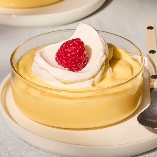 Glass filled with homemade lemon pudding with whipped cream on top.