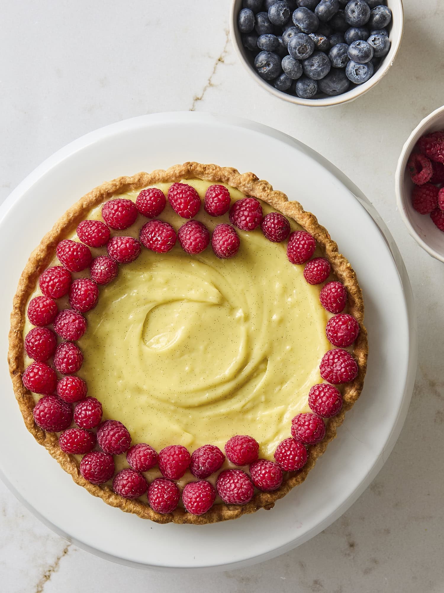 Assembly of a fruit tart with raspberries.