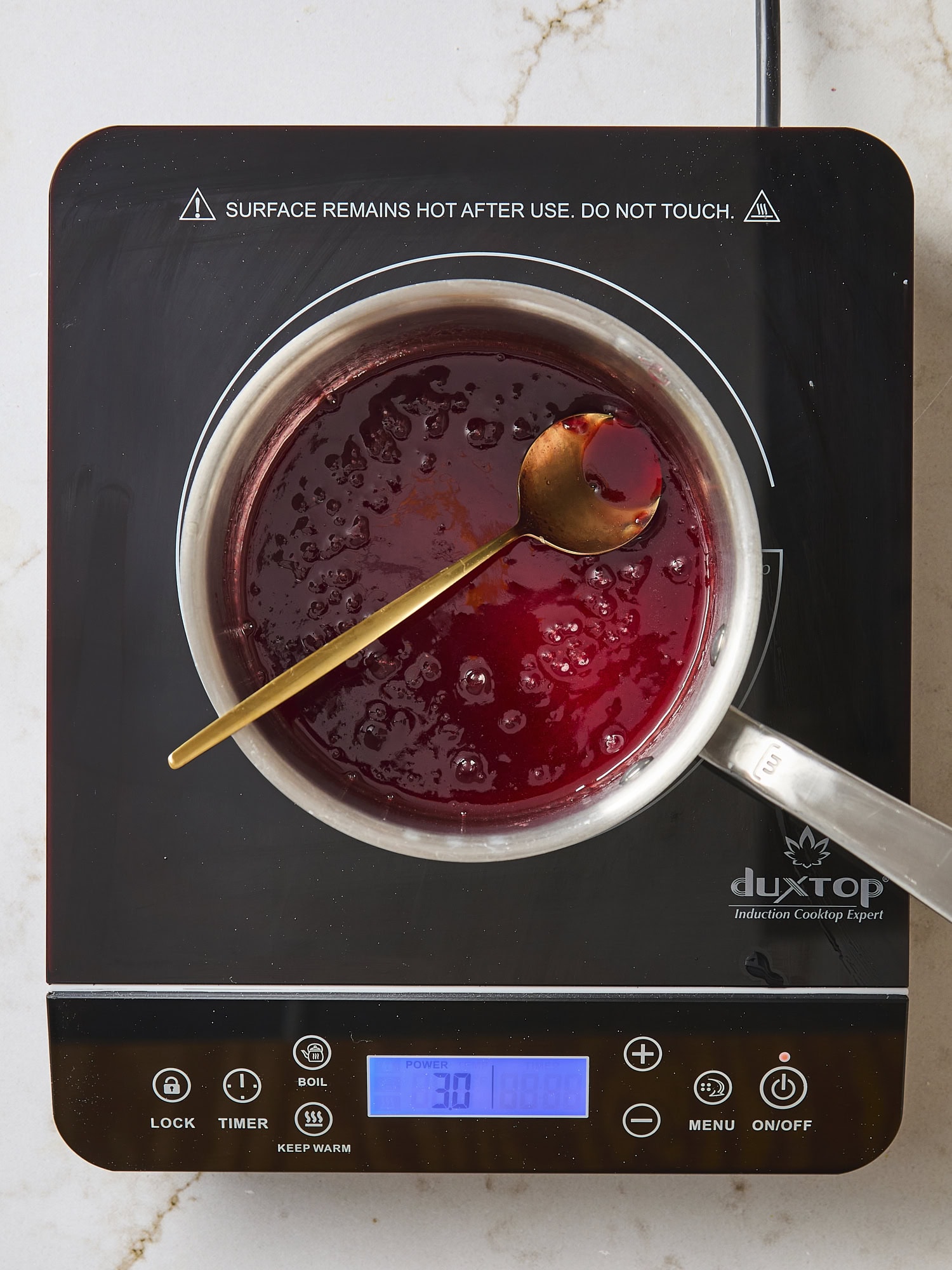 Simple raspberry jam glaze heating in saucepan.