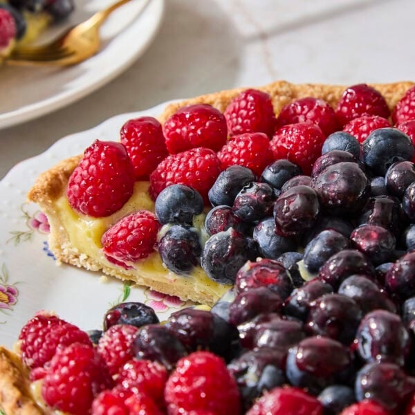 Slice taken out of fruit tart with pastry cream and berries.