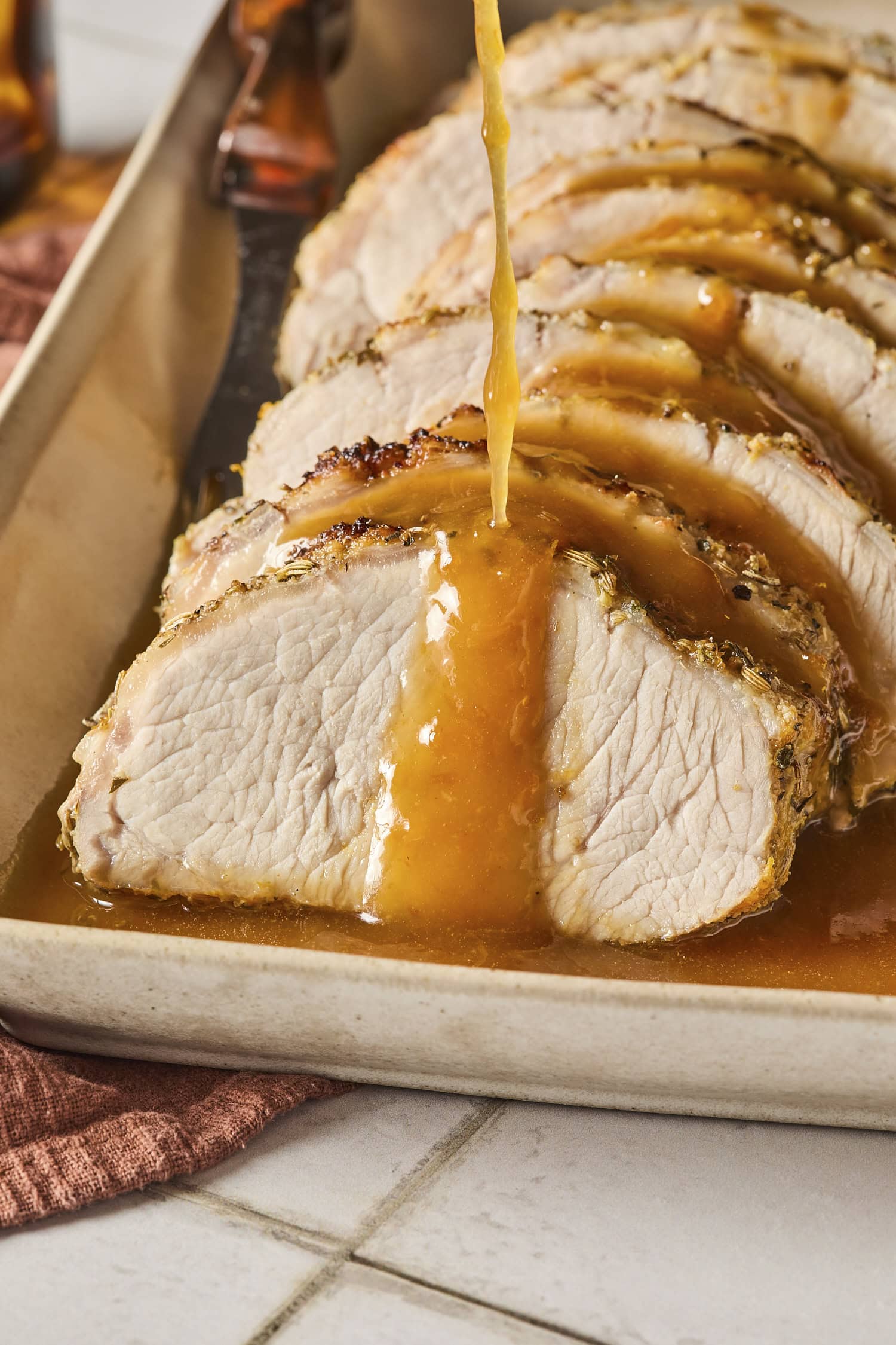 Citrus glaze being poured on top of pieces of pork roast.
