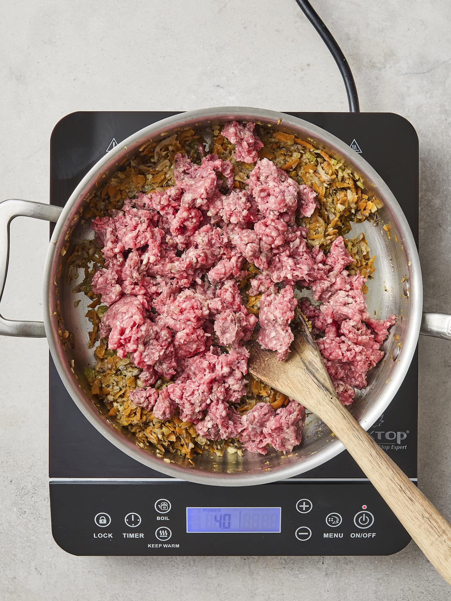 Uncooked ground beef in skillet for ragu.