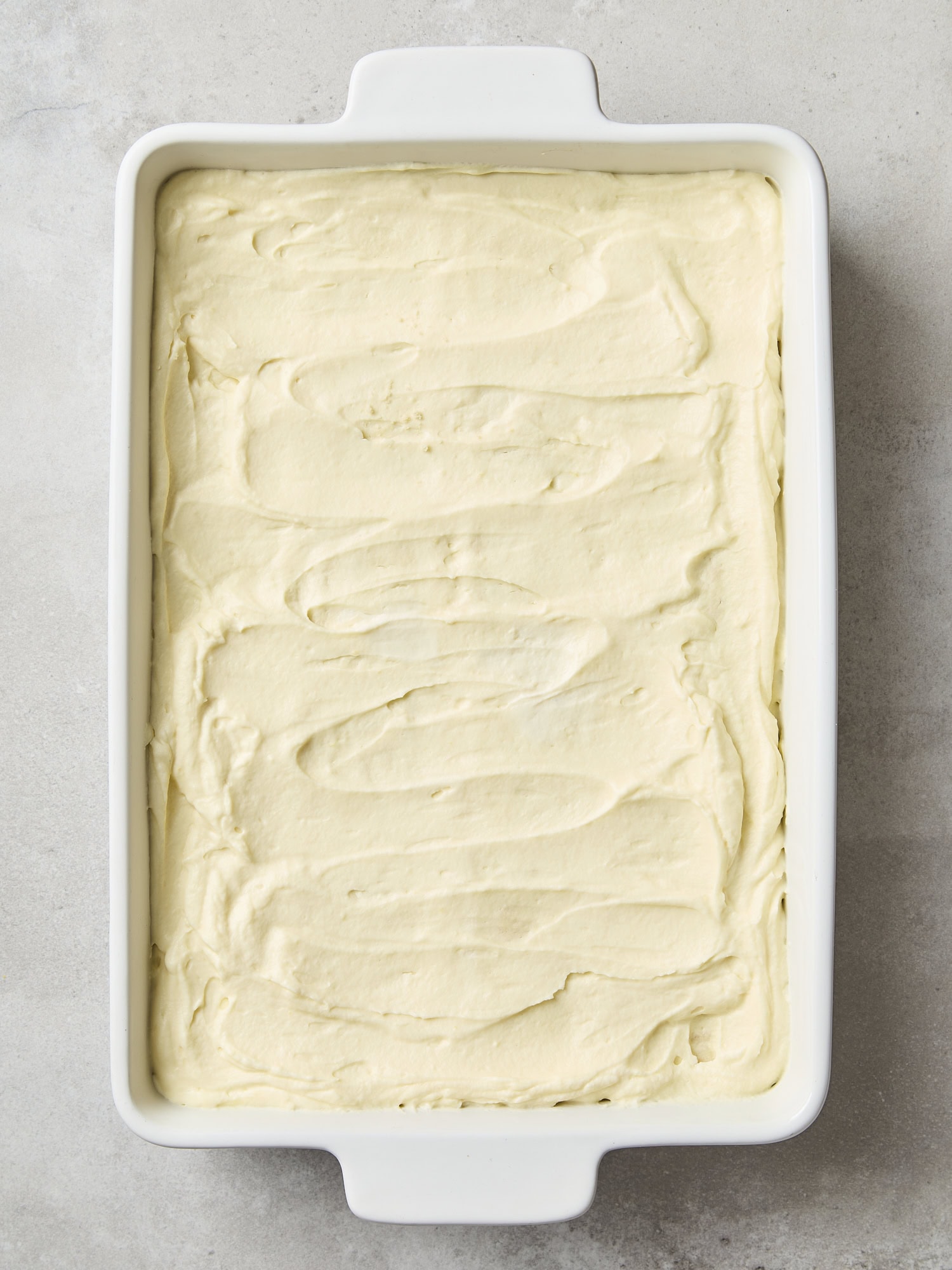 Baking dish with lemon pudding and whipped cream layered on cookies.