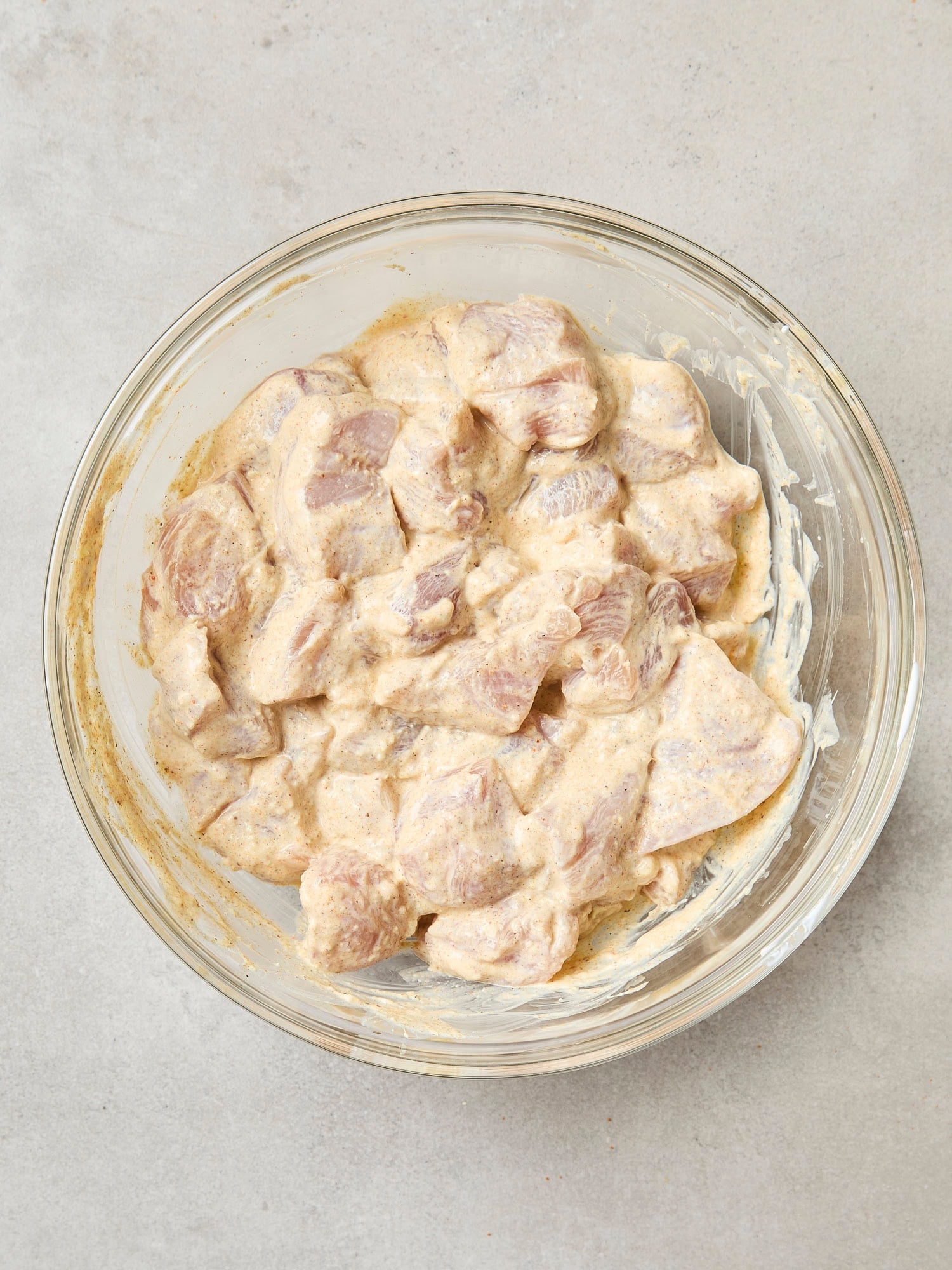 Glass bowl with marinating chicken.