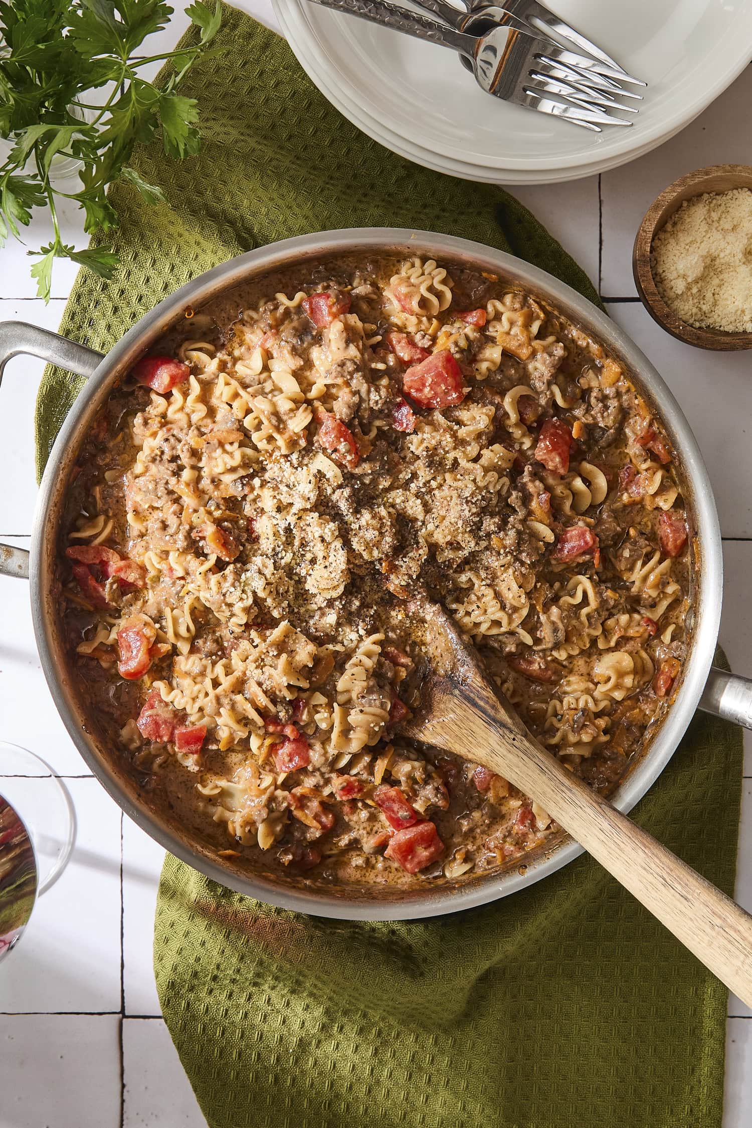 Skillet of beef ragu with wooden spoon scooping up a serving.