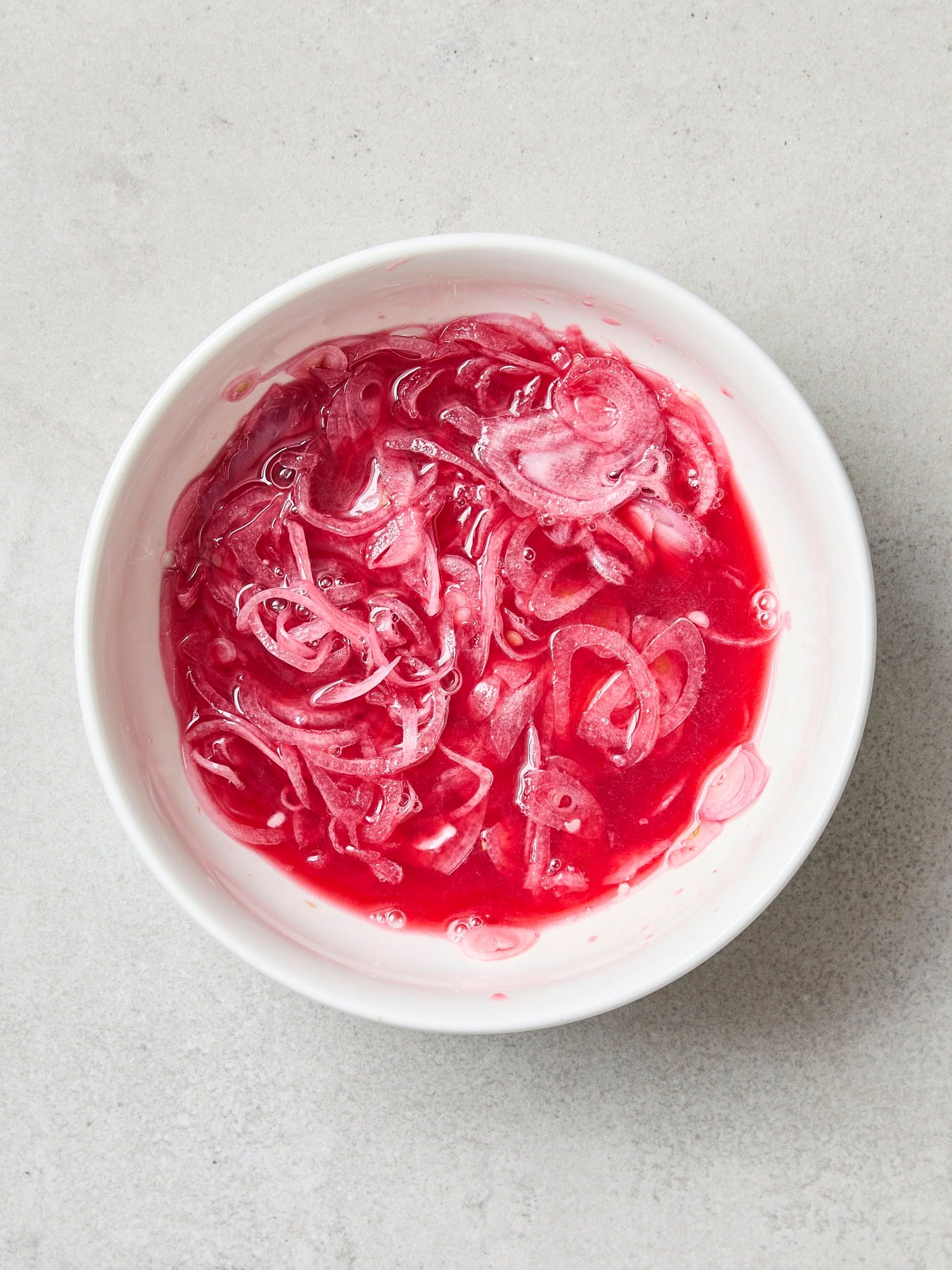 Sliced shallot being pickled in a small bowl.