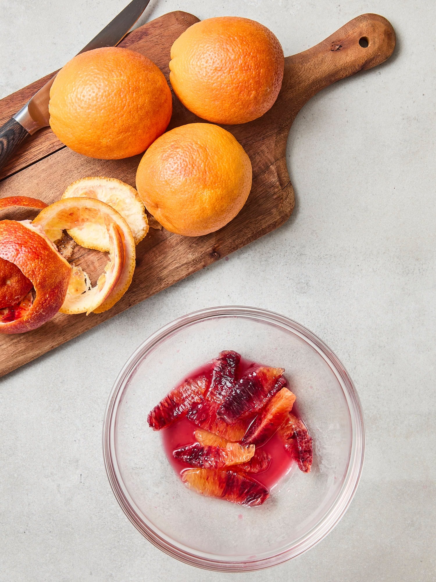 Blood oranges being segmented into a bowl.