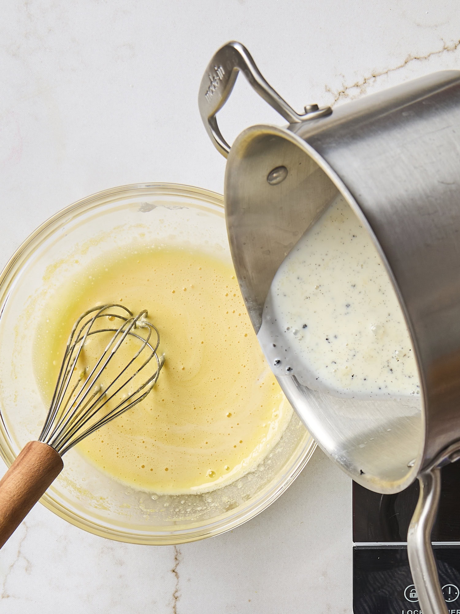 Tempering egg yolk mixture into milk mixture for pastry cream.