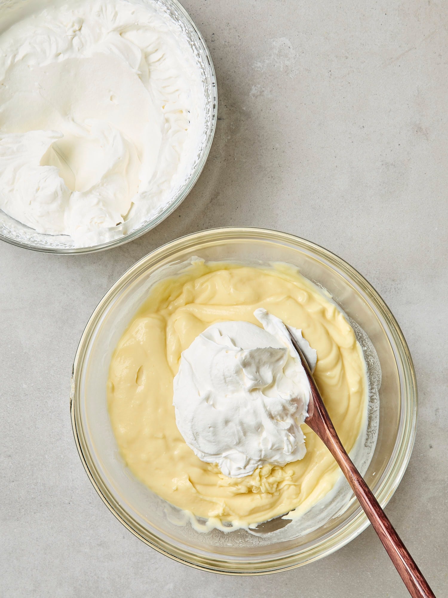 One bowl with whipped cream and another with lemon pudding.