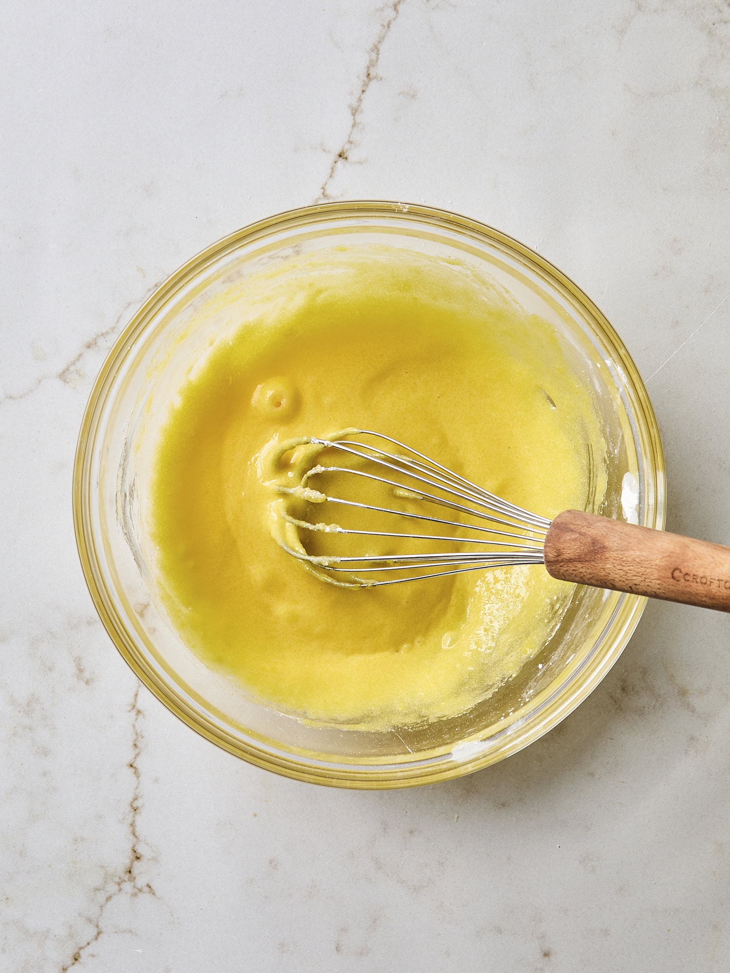 Whisked egg yolks in a glass bowl.