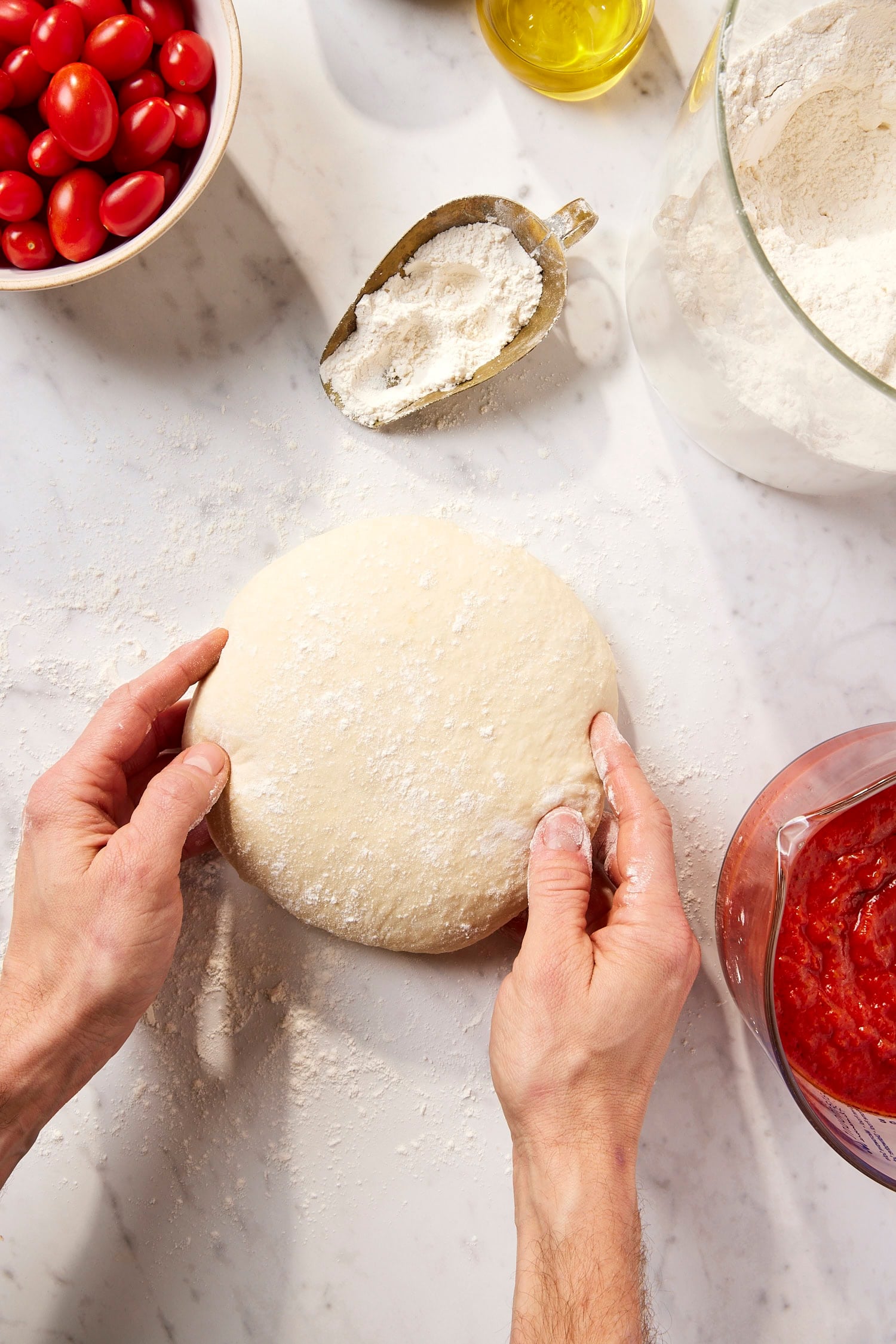 Two hands rolling up pizza dough recipe.