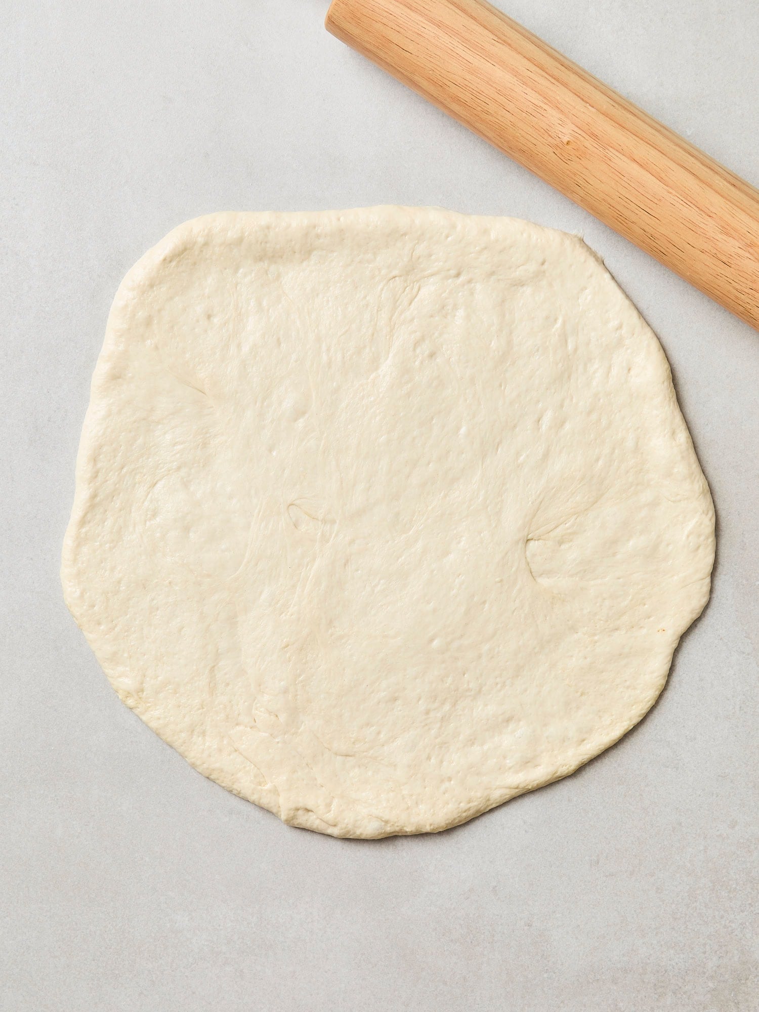 Pizza dough rolled out into a 14-inch circle.