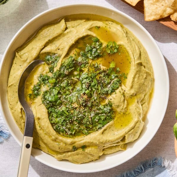 Bowl of creamy avocado hummus with cilantro sauce on top.