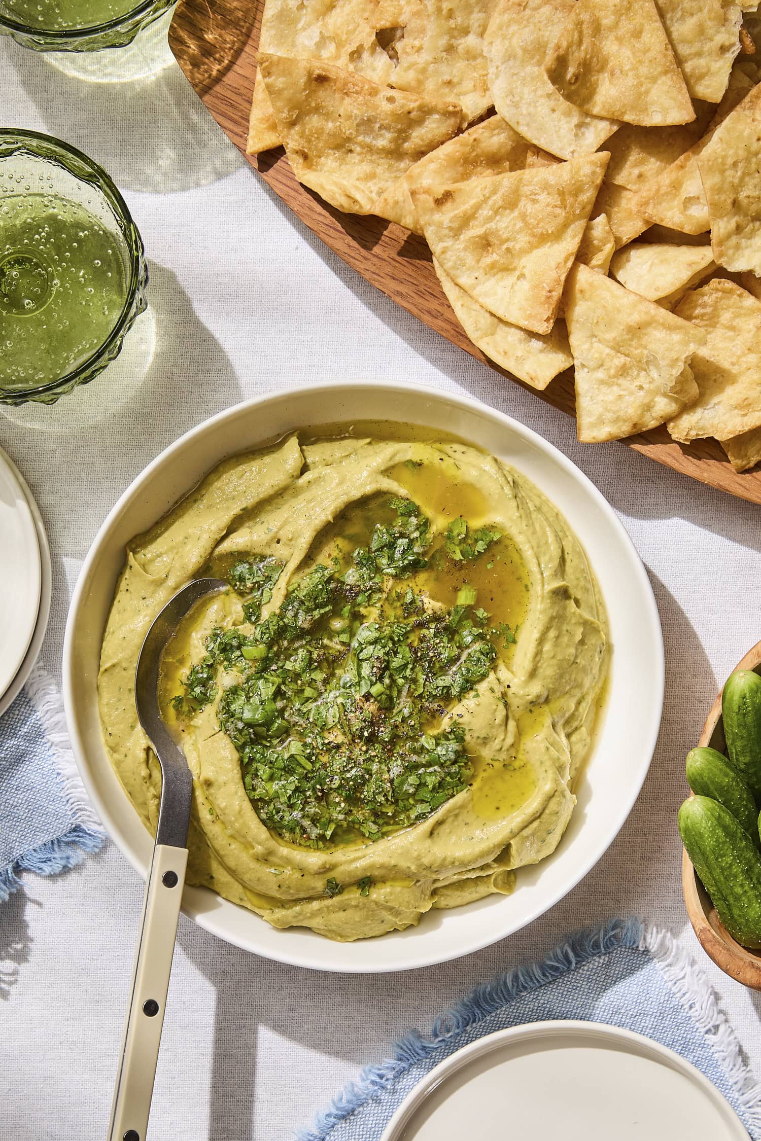 Bowl with avocado hummus with pita chips to the side.