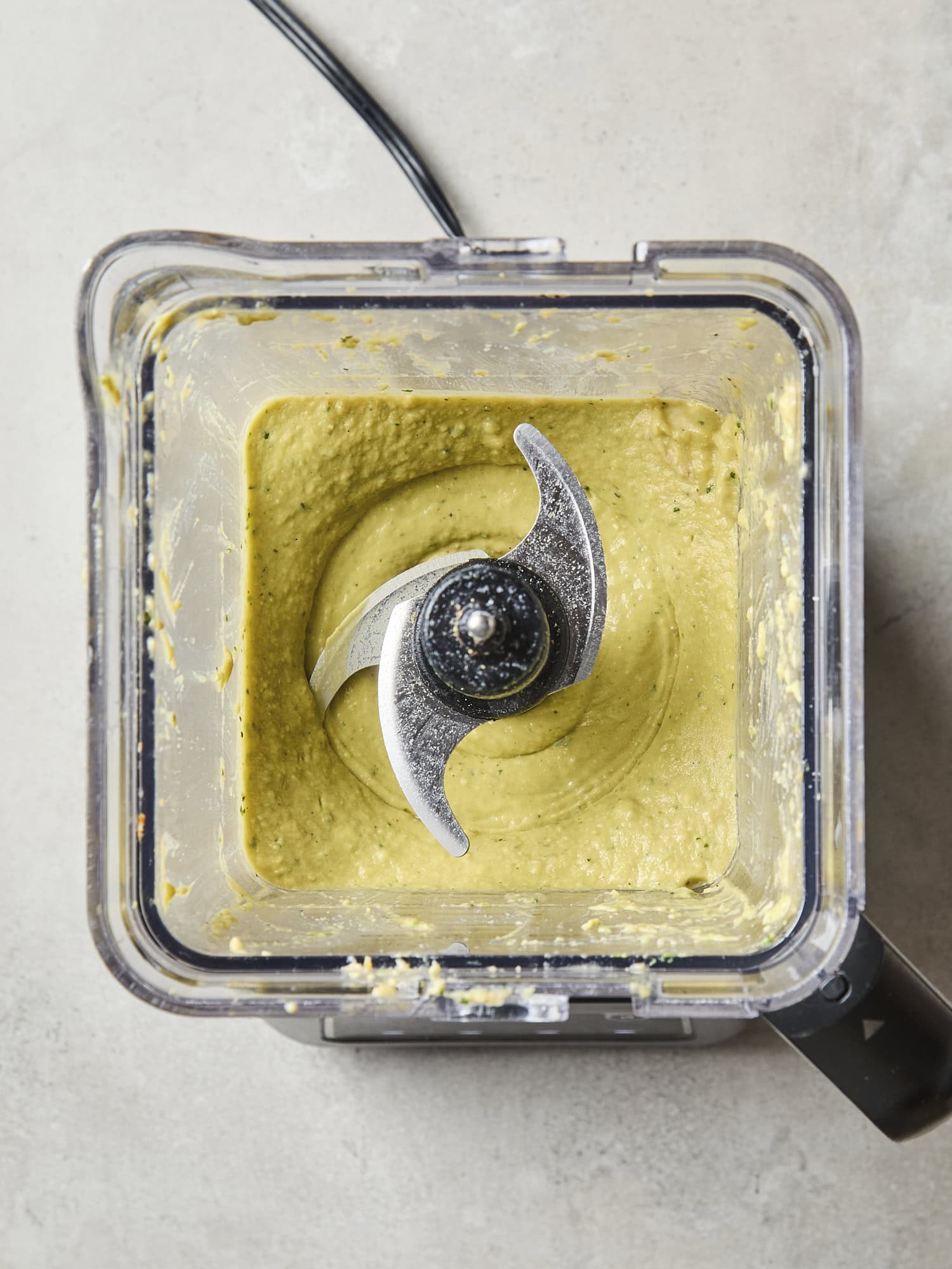 Blender with blended green hummus mixture.