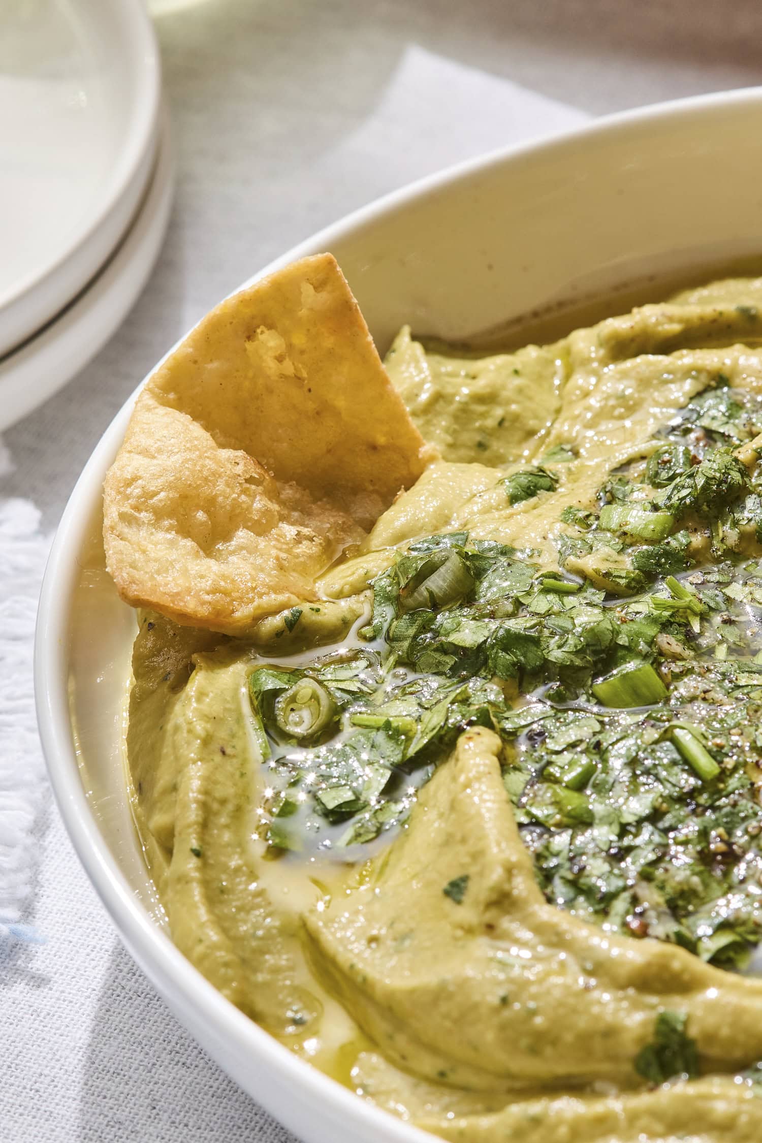Pita chip dipping into avocado hummus.