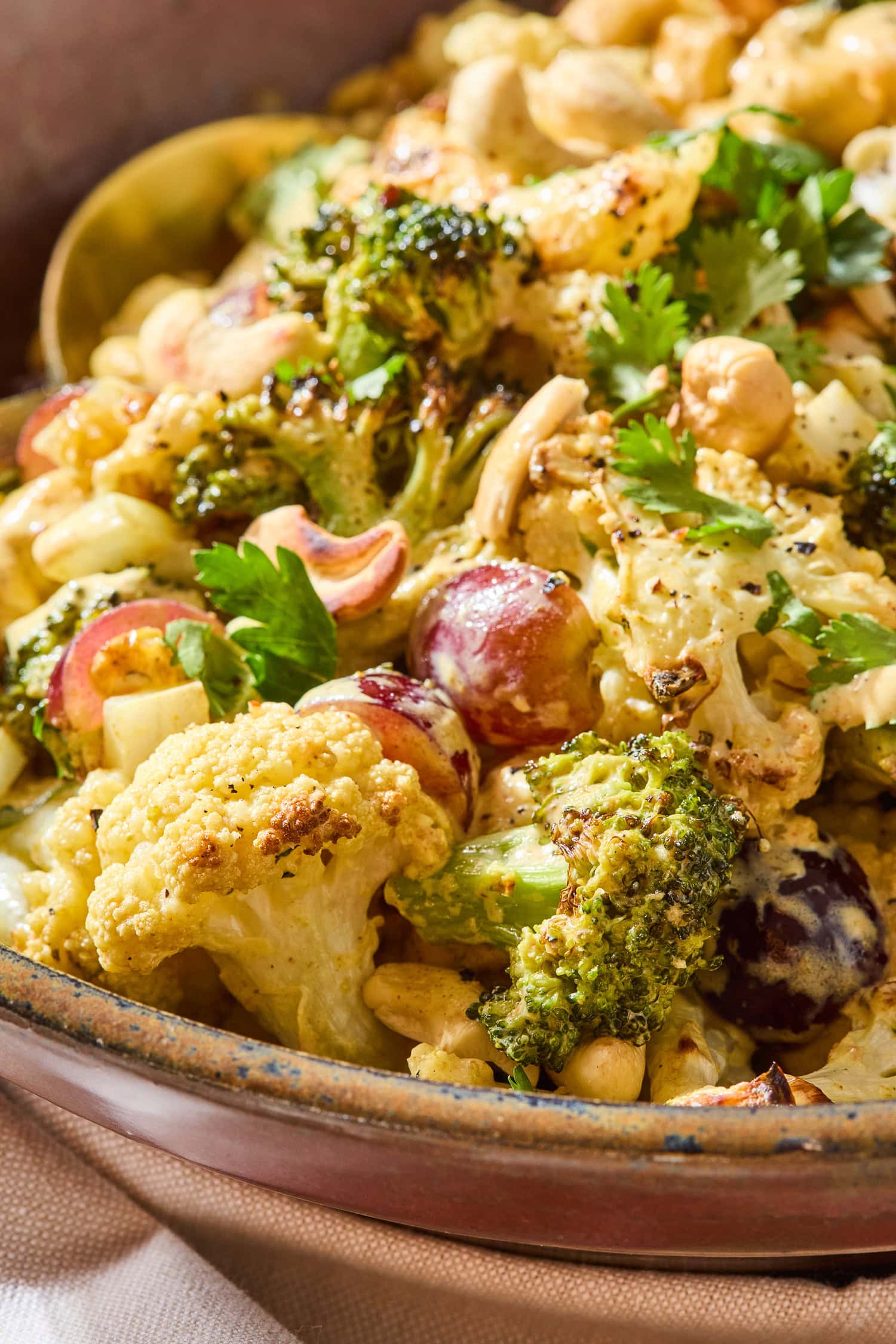 Roasted cualiflower and broccoli covered in curry dressing in a serving bowl.