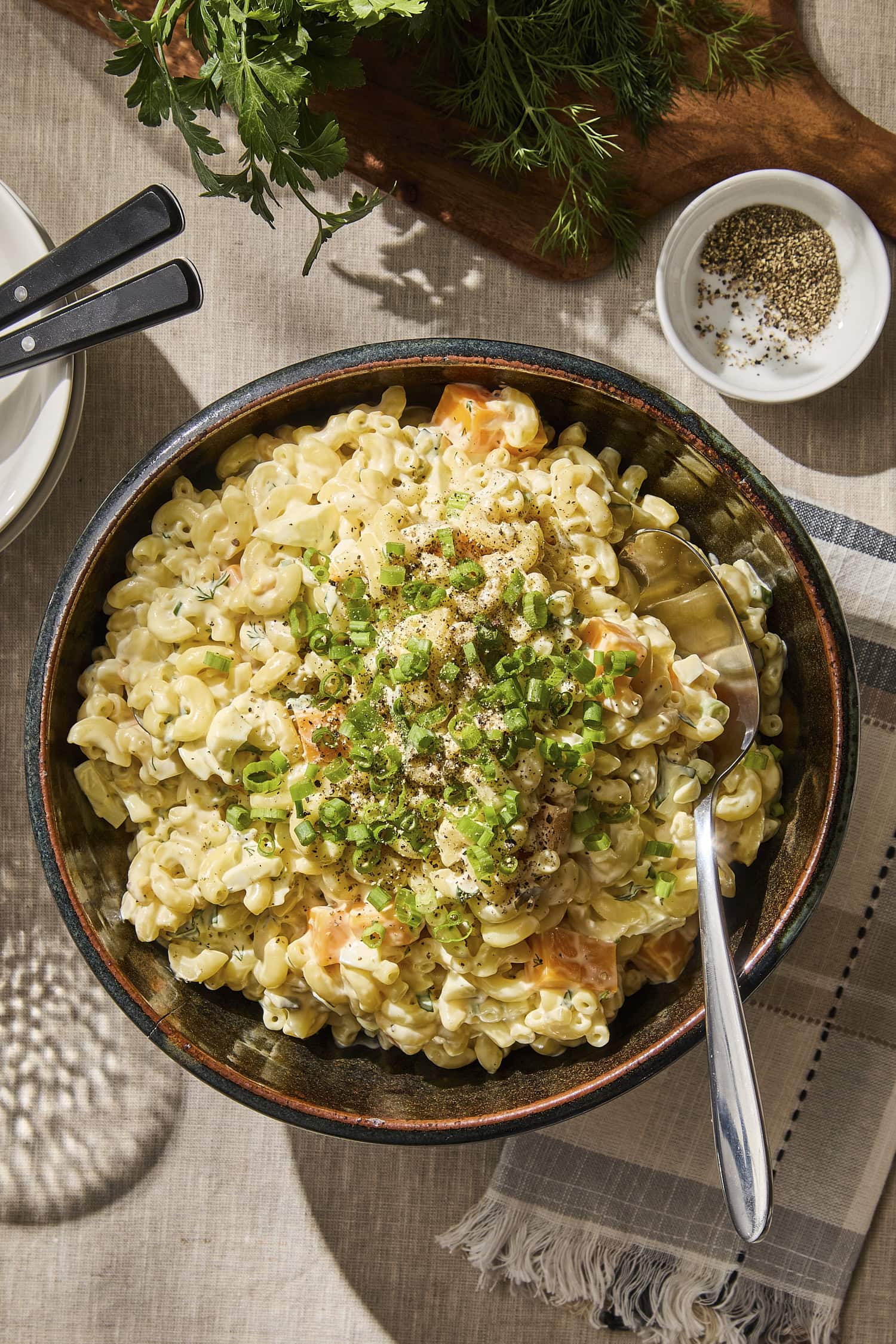 Macaroni salad in a large bowl with serving spoon.