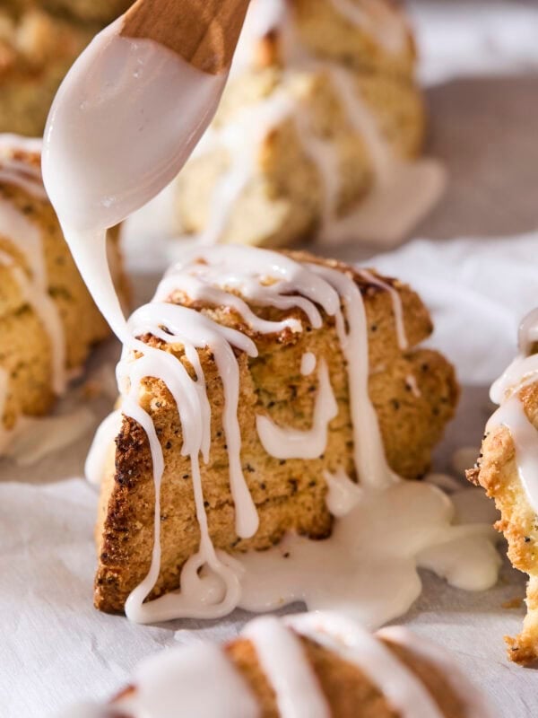 Glaze being drizzled on top of poppy seed scones.