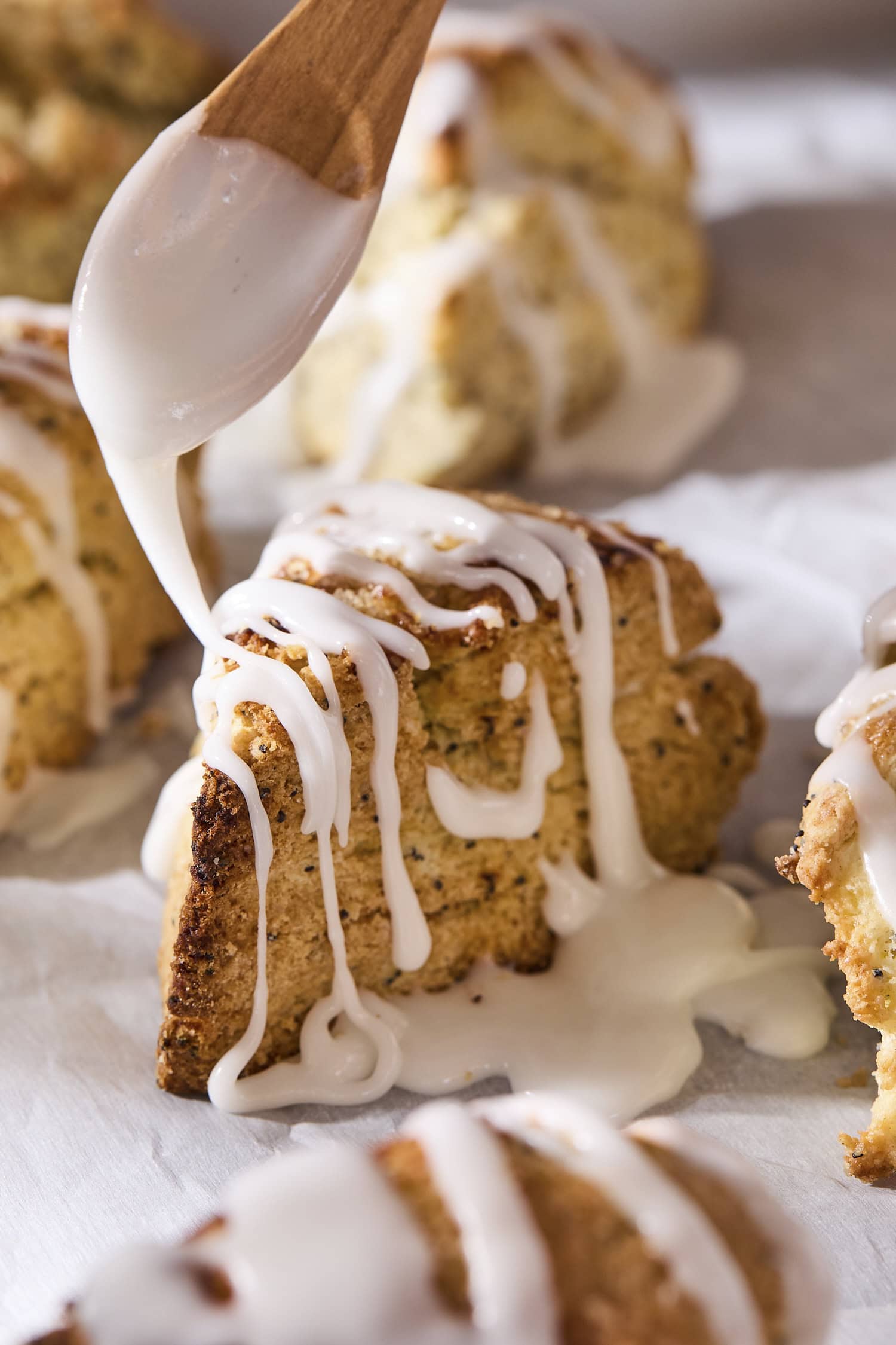 Glaze being drizzled on top of poppy seed scones.