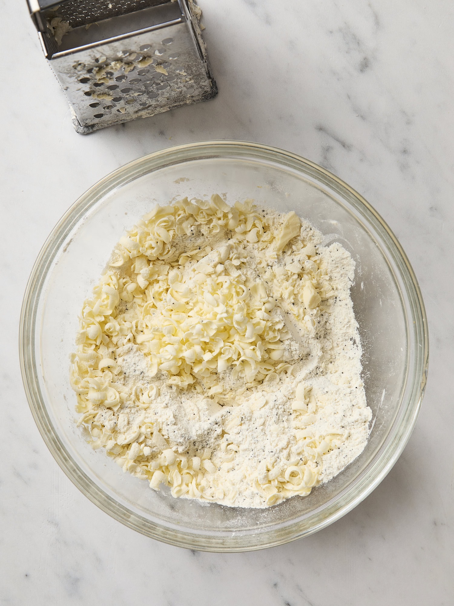 Grated butter with dry ingredients for lemon poppy seed scones.