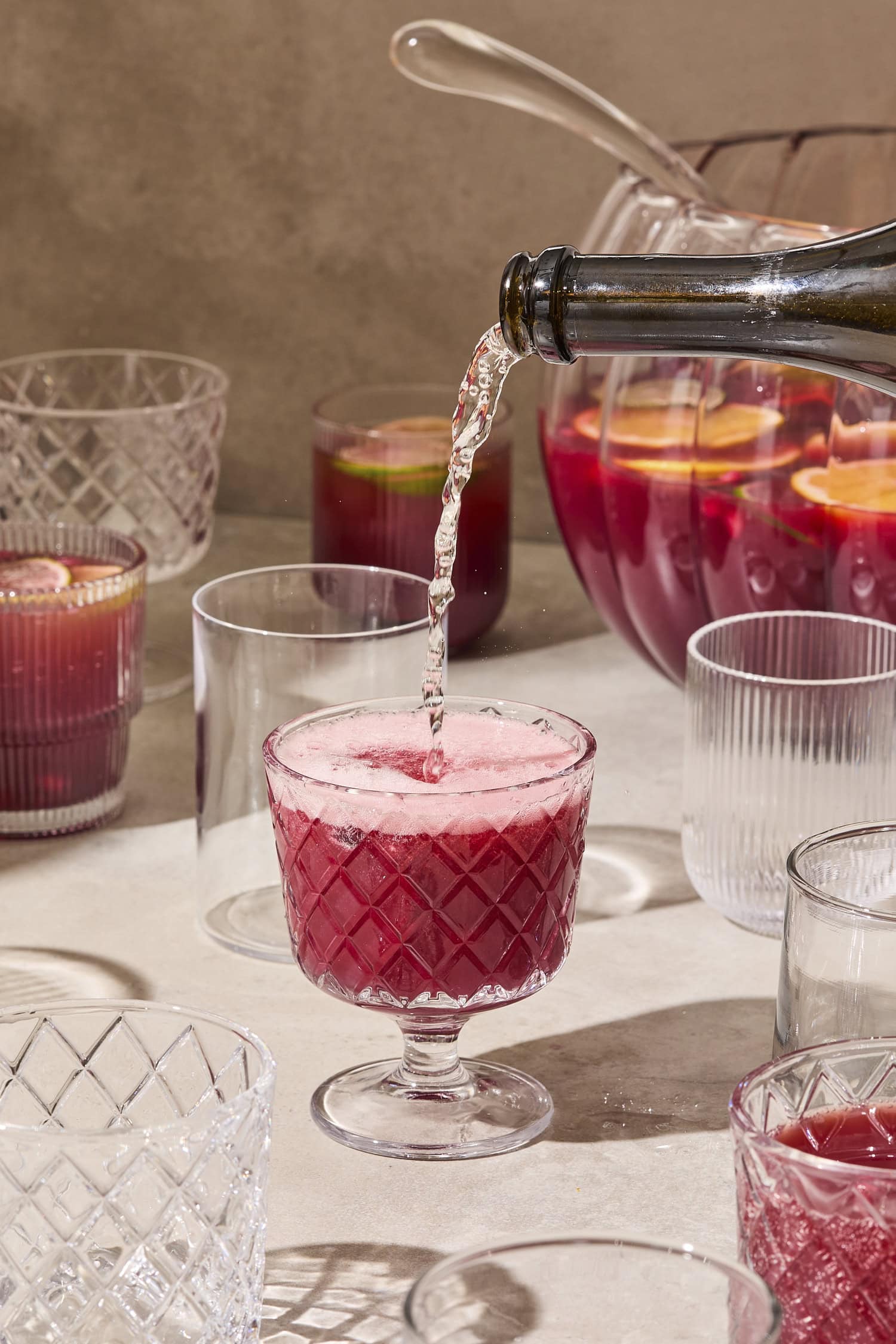 Champagne pouring on top of pomegranate punch.
