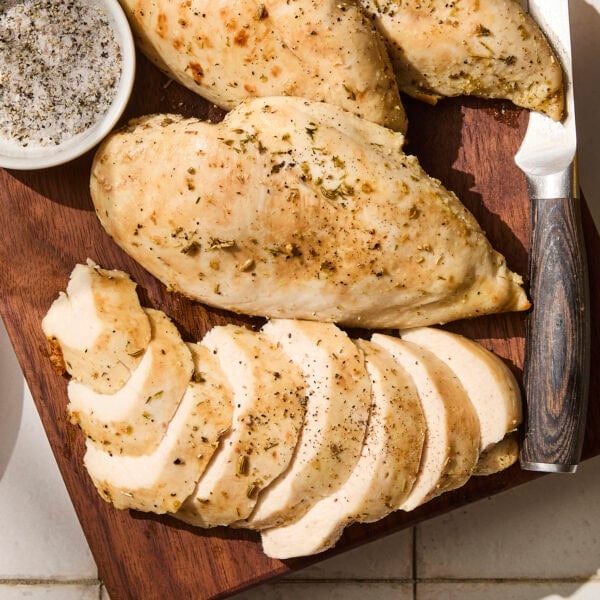 Sliced baked chicken breast on a cutting board.