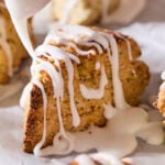 Lemon glaze being drizzled on top of poppy seed scones.