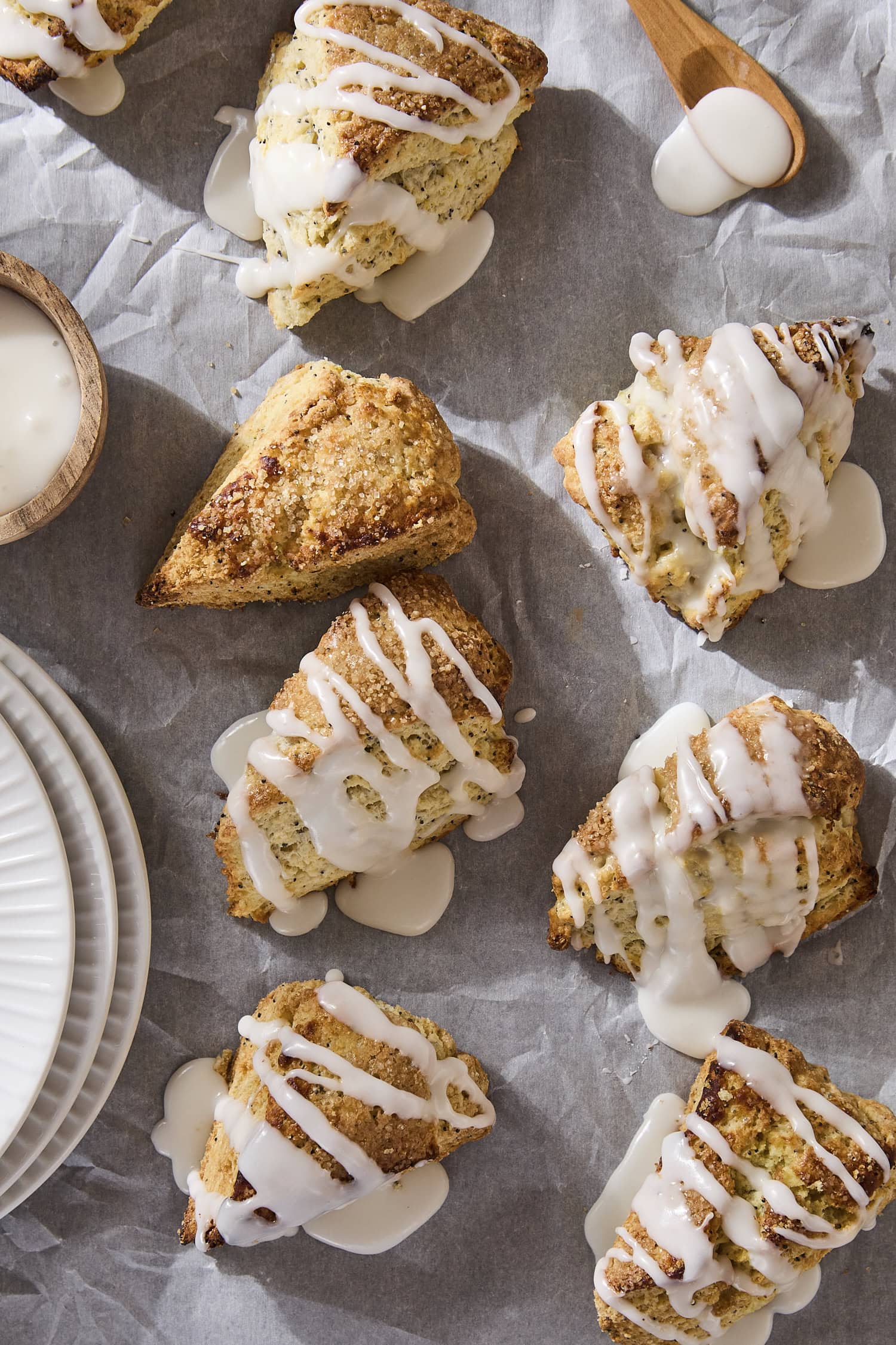 Glazed lemon poppy seed scones on parchment paper.