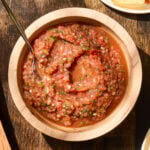Wooden bowl filled with salsa with spoon.