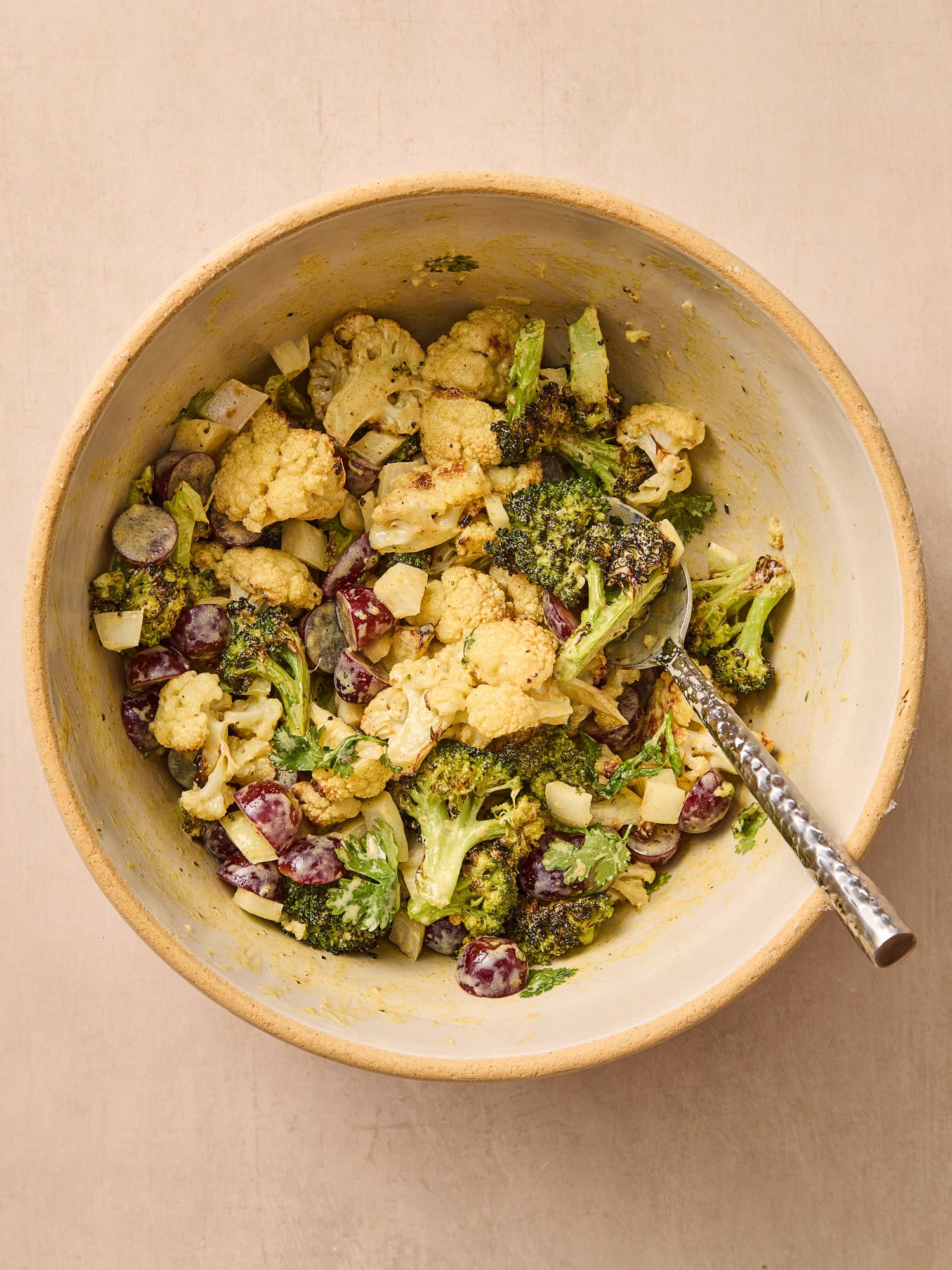 Adding additional ingredients to a curry broccoli and cauliflower salad.