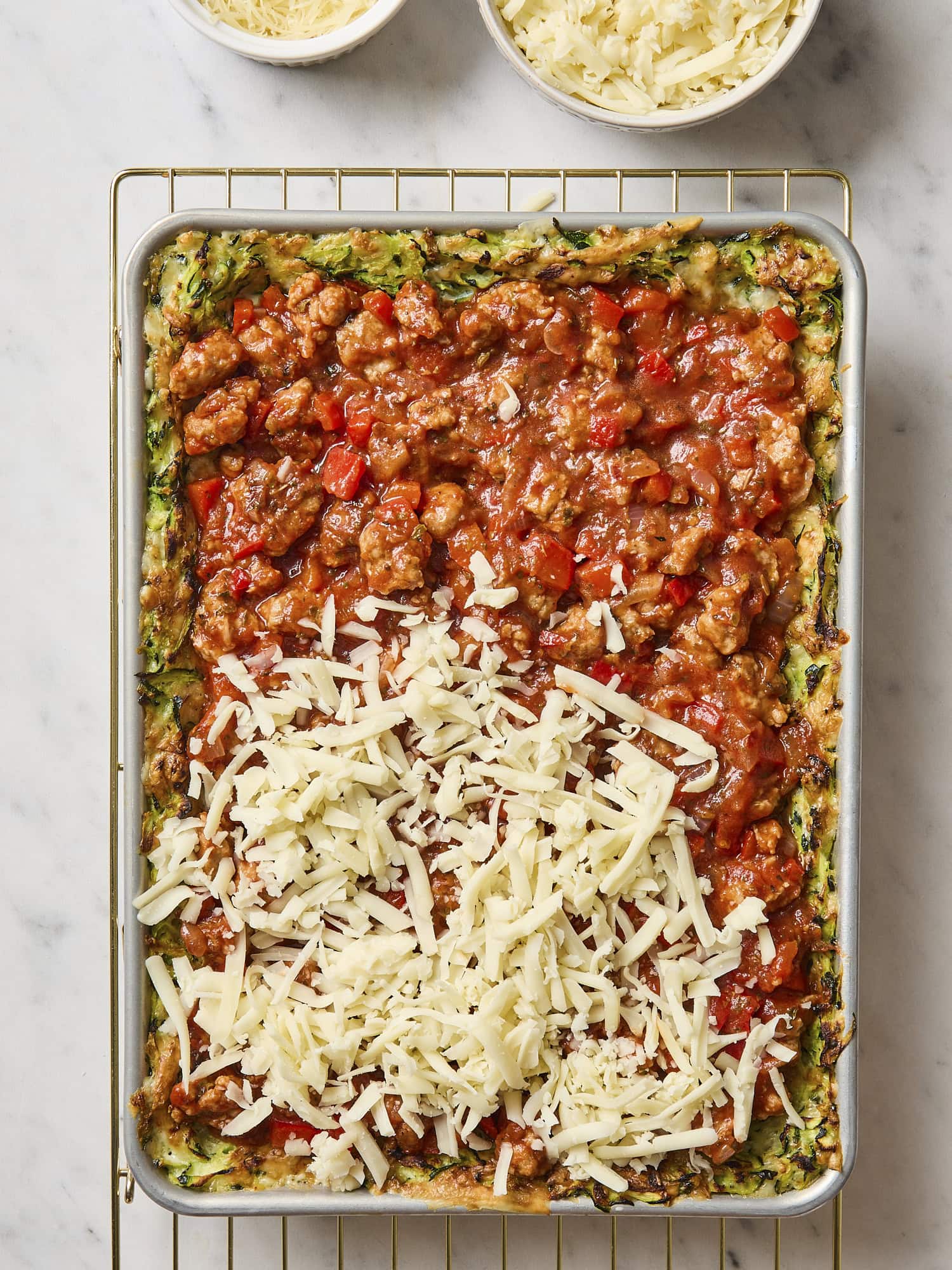 Cheese being added on top of pizza sauce for casserole.