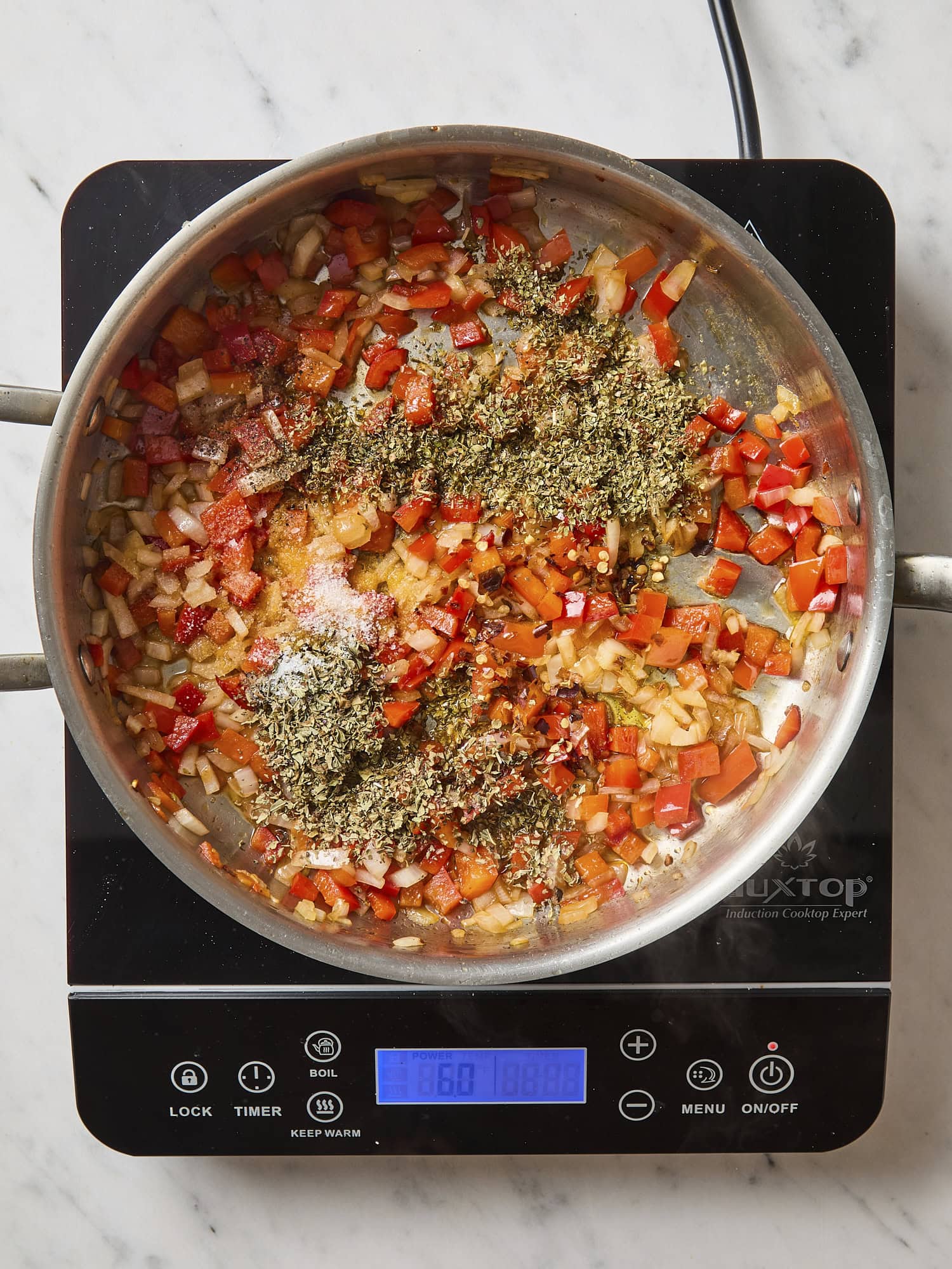 Cooking mixture of onion and bell pepper in skillet.