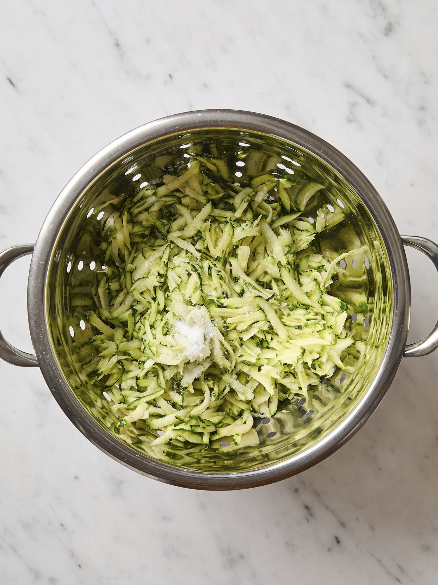 Salting zucchini in strainer.